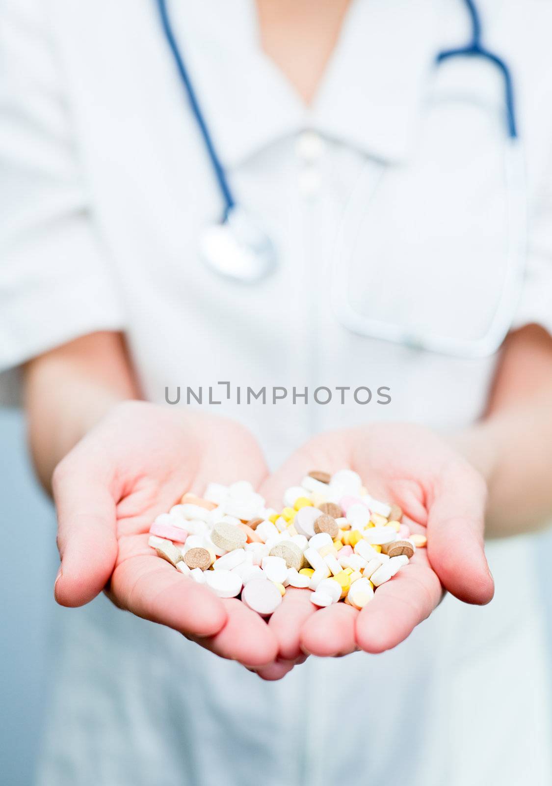 Closeup of doctor holding heap of tablets in her hand, focus on tablets