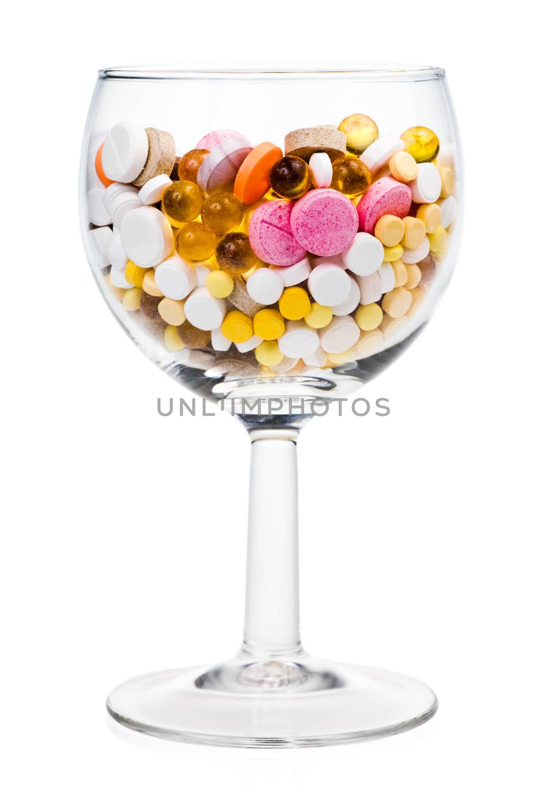 Various tablets in wineglass on white background