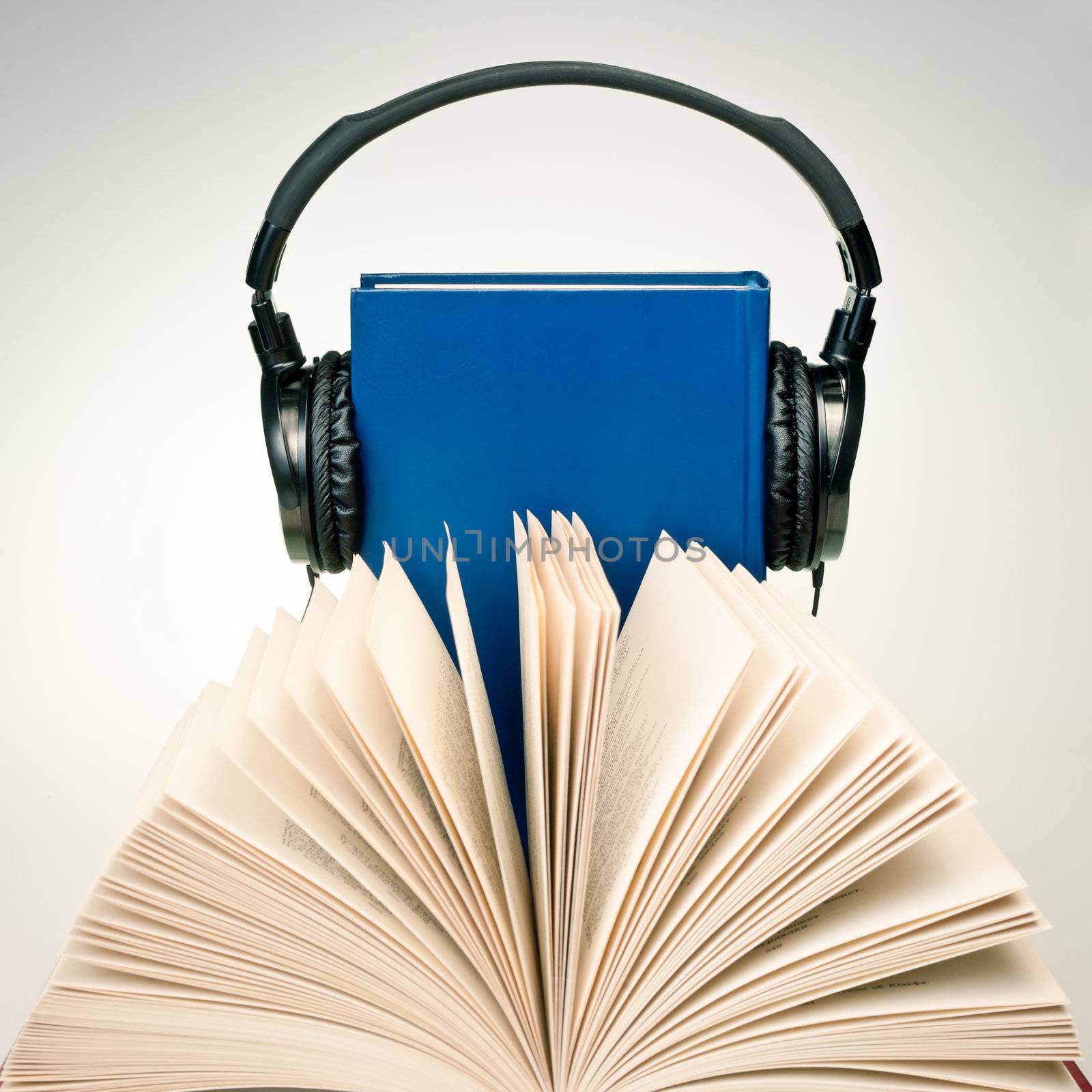 Open book with HI-Fi headphones on a blue book at background