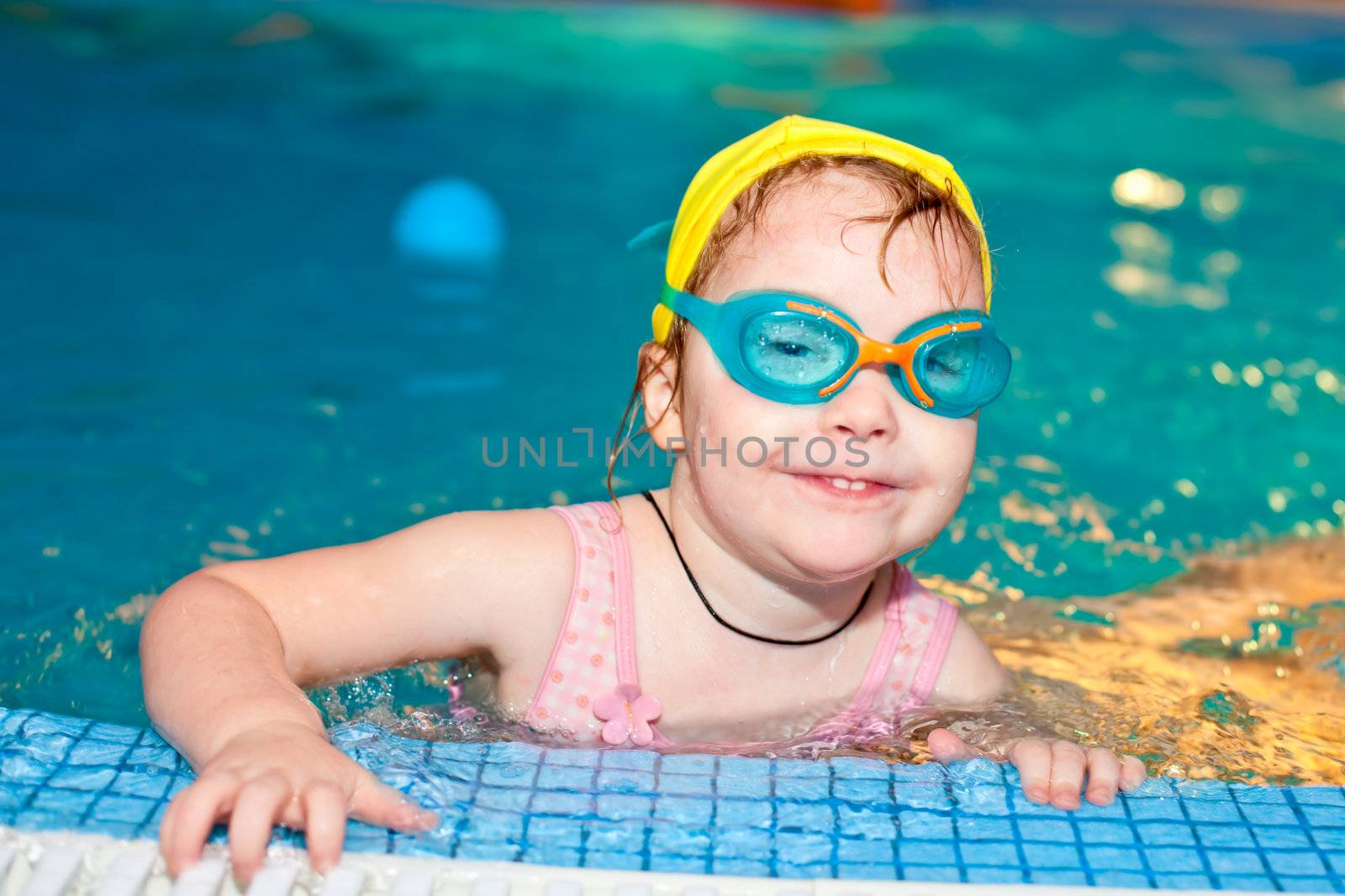 Little girl wearing goggles in a swimming pool