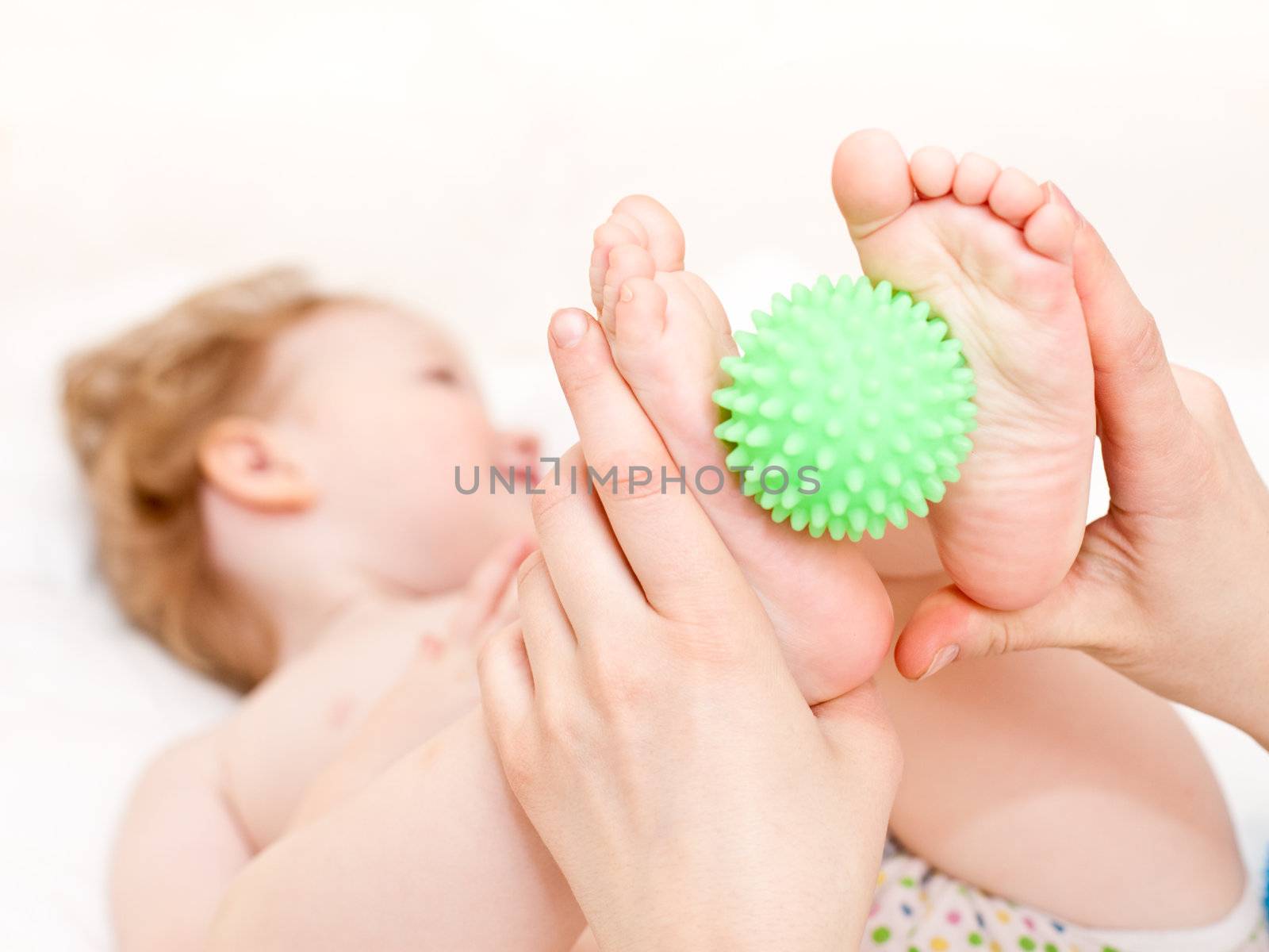 Masseur massaging child's feet with rubber device, shallow focus