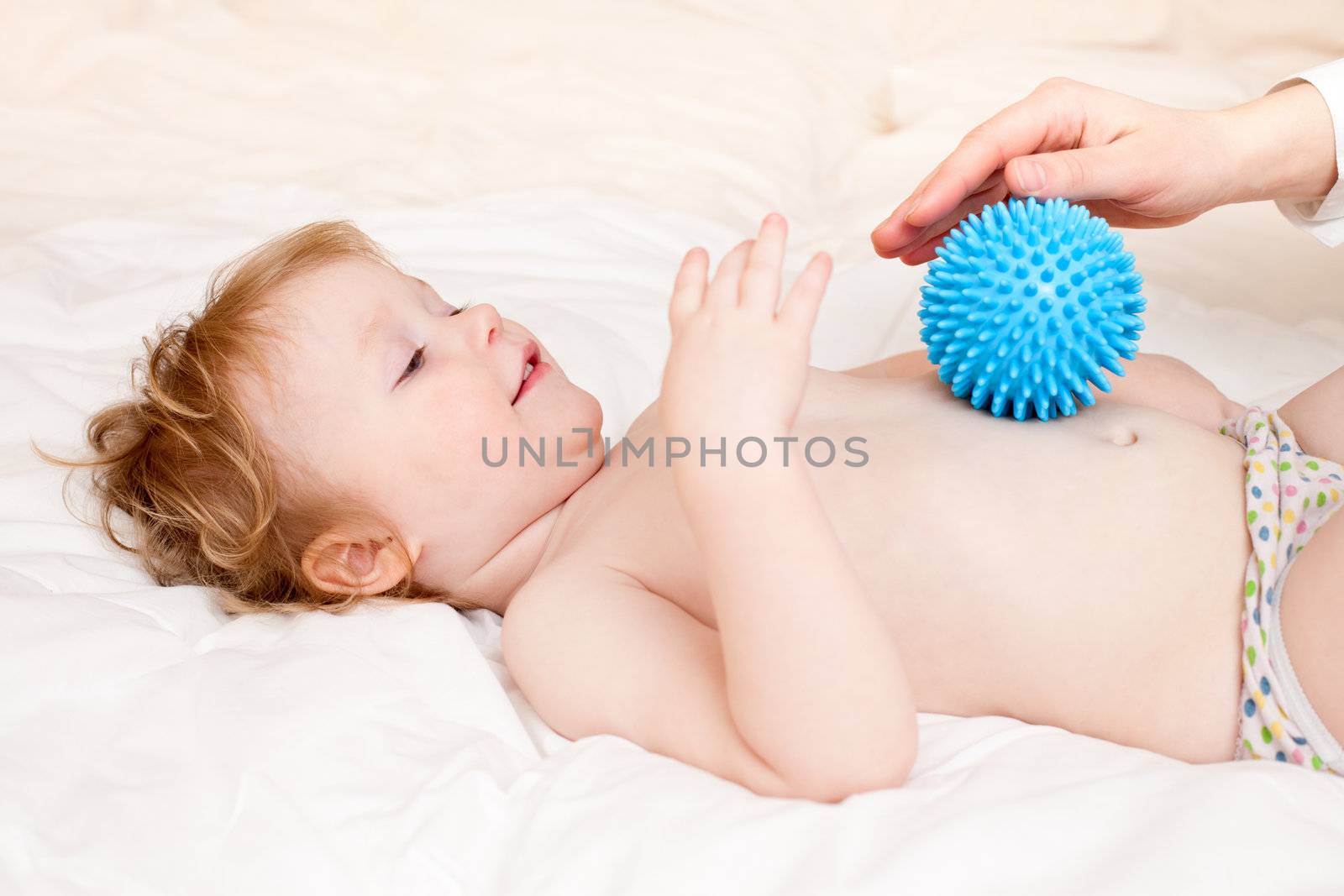 Masseur massaging little girl with rubber device, shallow focus