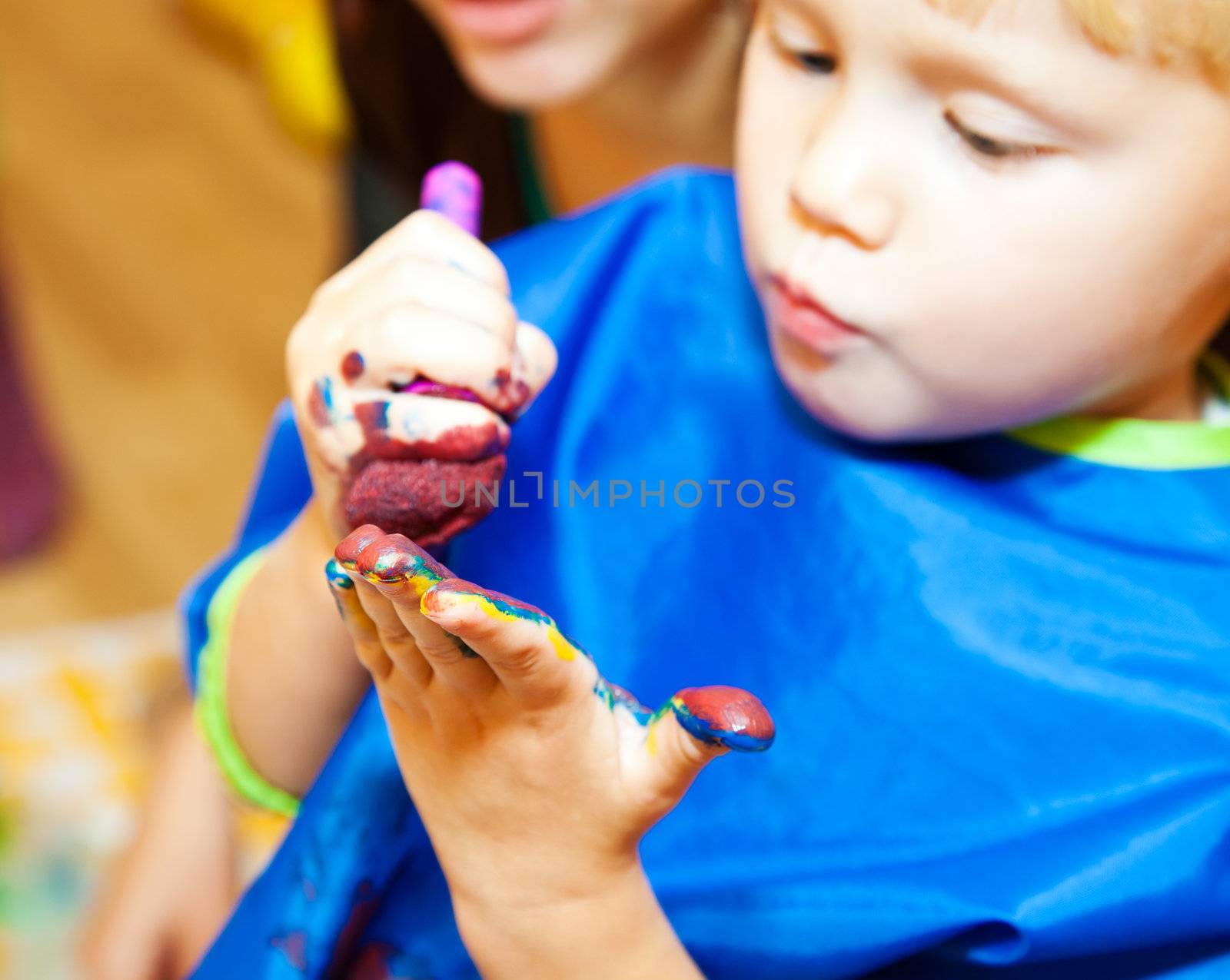 Little girl with paint brush making a finger painting