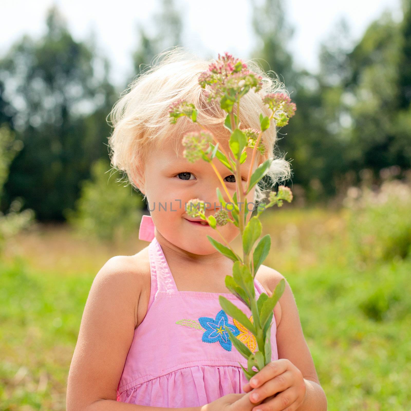 Portrait of cute little girl holding fower outdoors