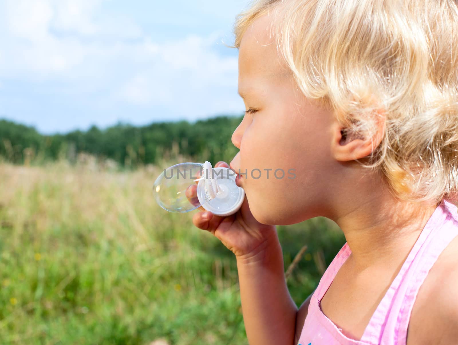 Cute little girl making soap bubbles outdoors