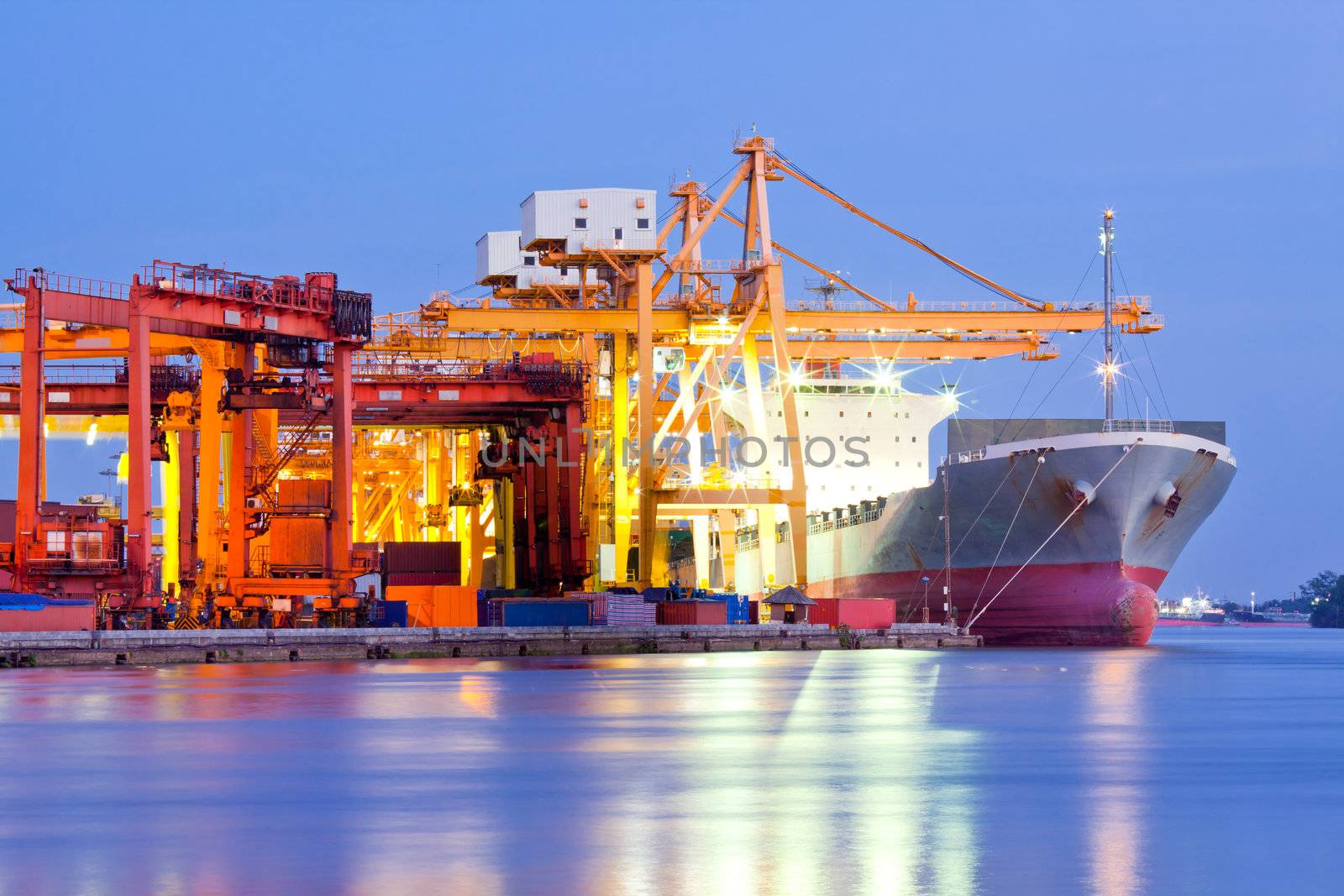 Industrial Container Cargo freight ship with working crane bridge in shipyard at dusk for Logistic Import Export background