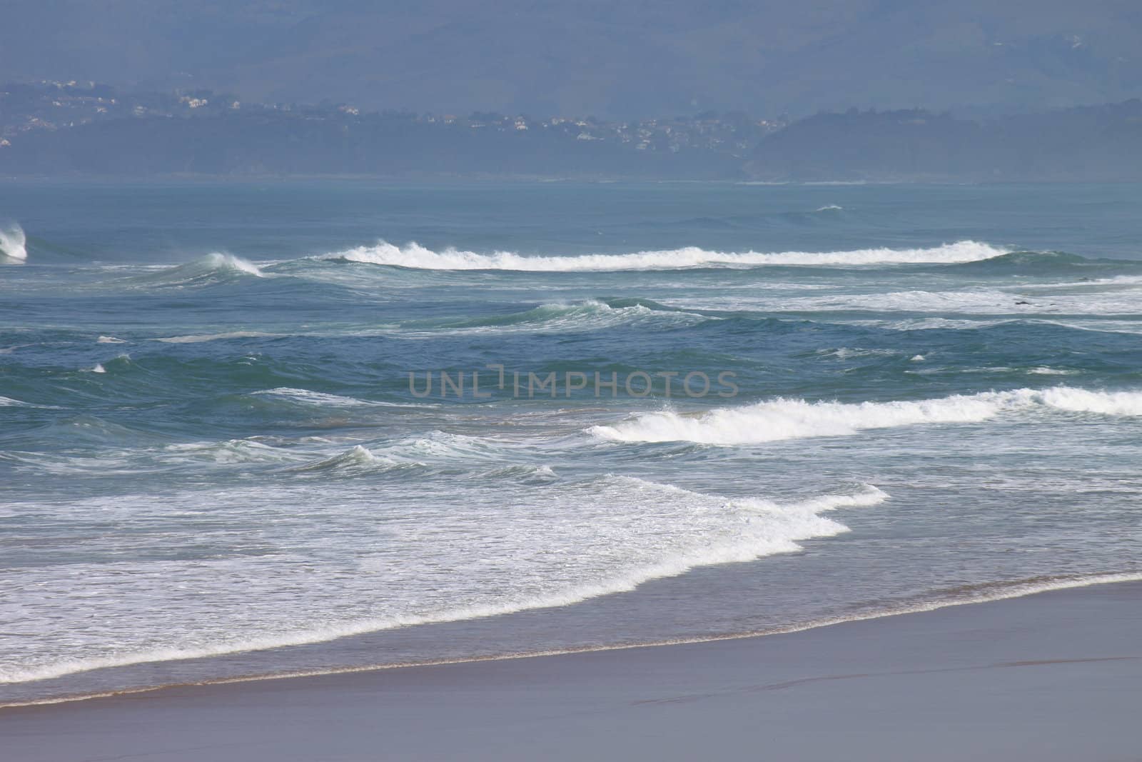 panoramic views of the ocean with its beach and waves over a blue sky