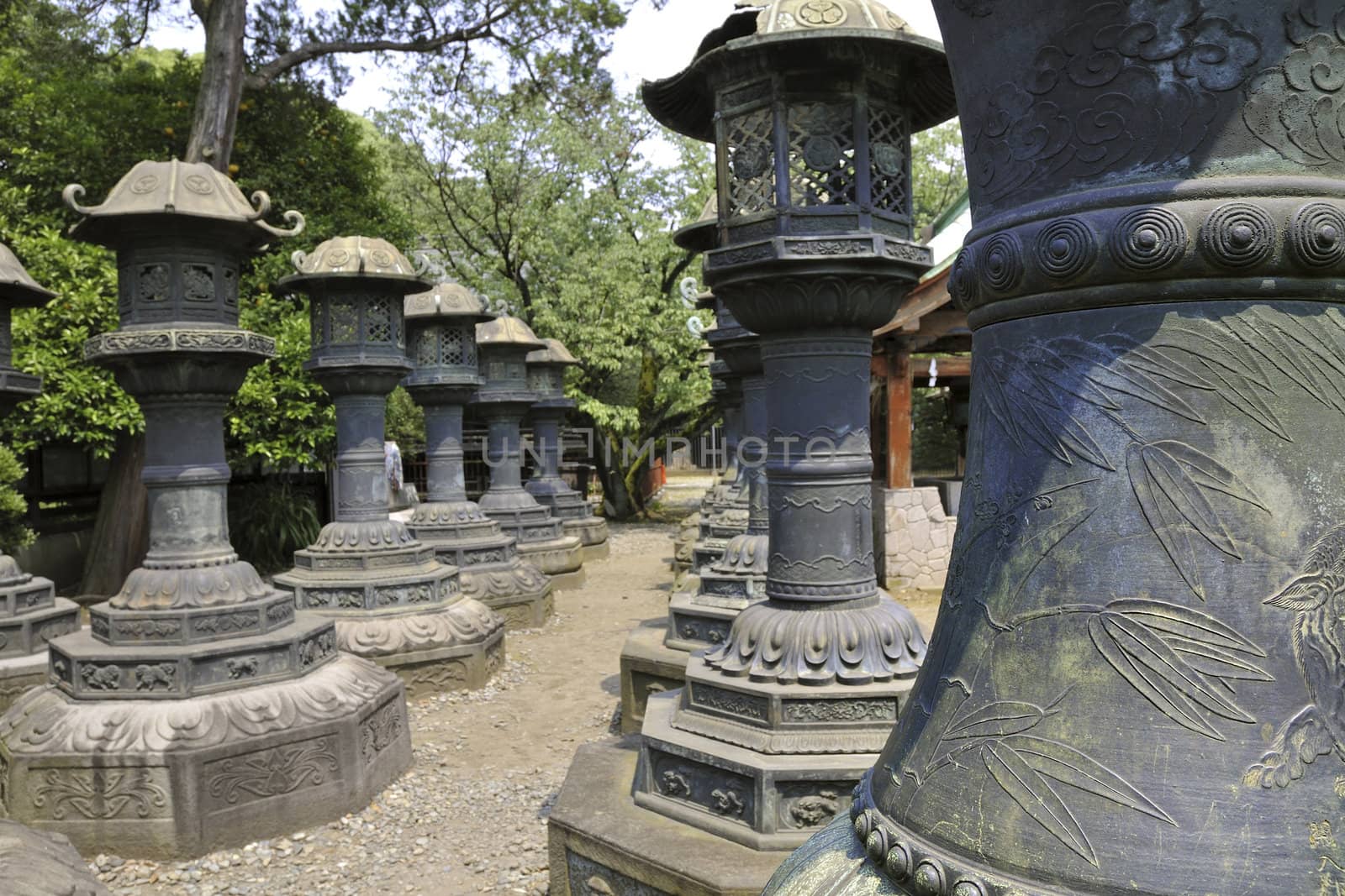 Rows of Japanese traditional stone lanterns in Tokyo Ueno park; focus on front lantern