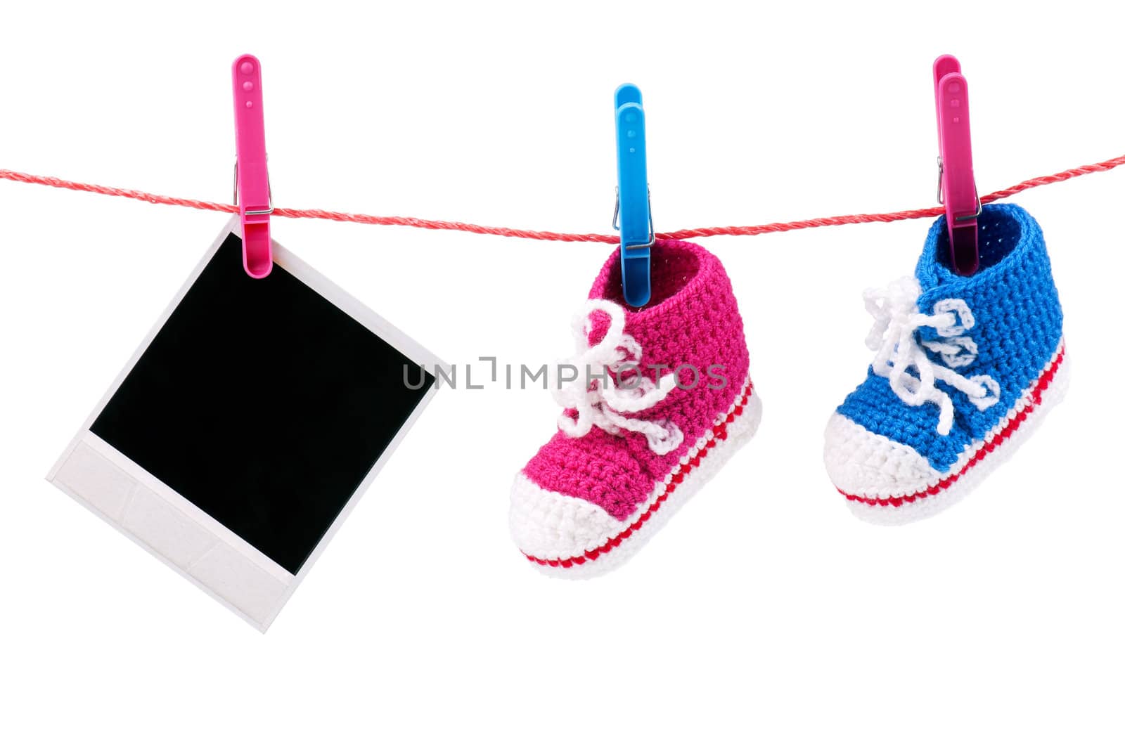 Baby bootees and photo hanging on the clothesline on a white background