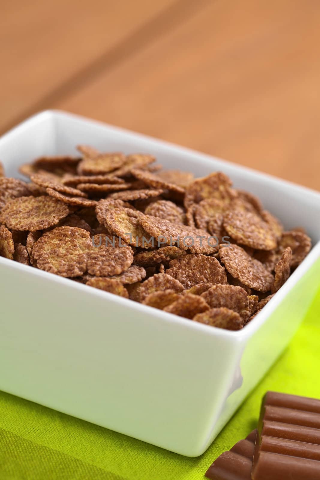 Bowl of chocolate corn flakes cereal with chocolate bars on the side (Selective Focus, Focus in the middle of the cereal)