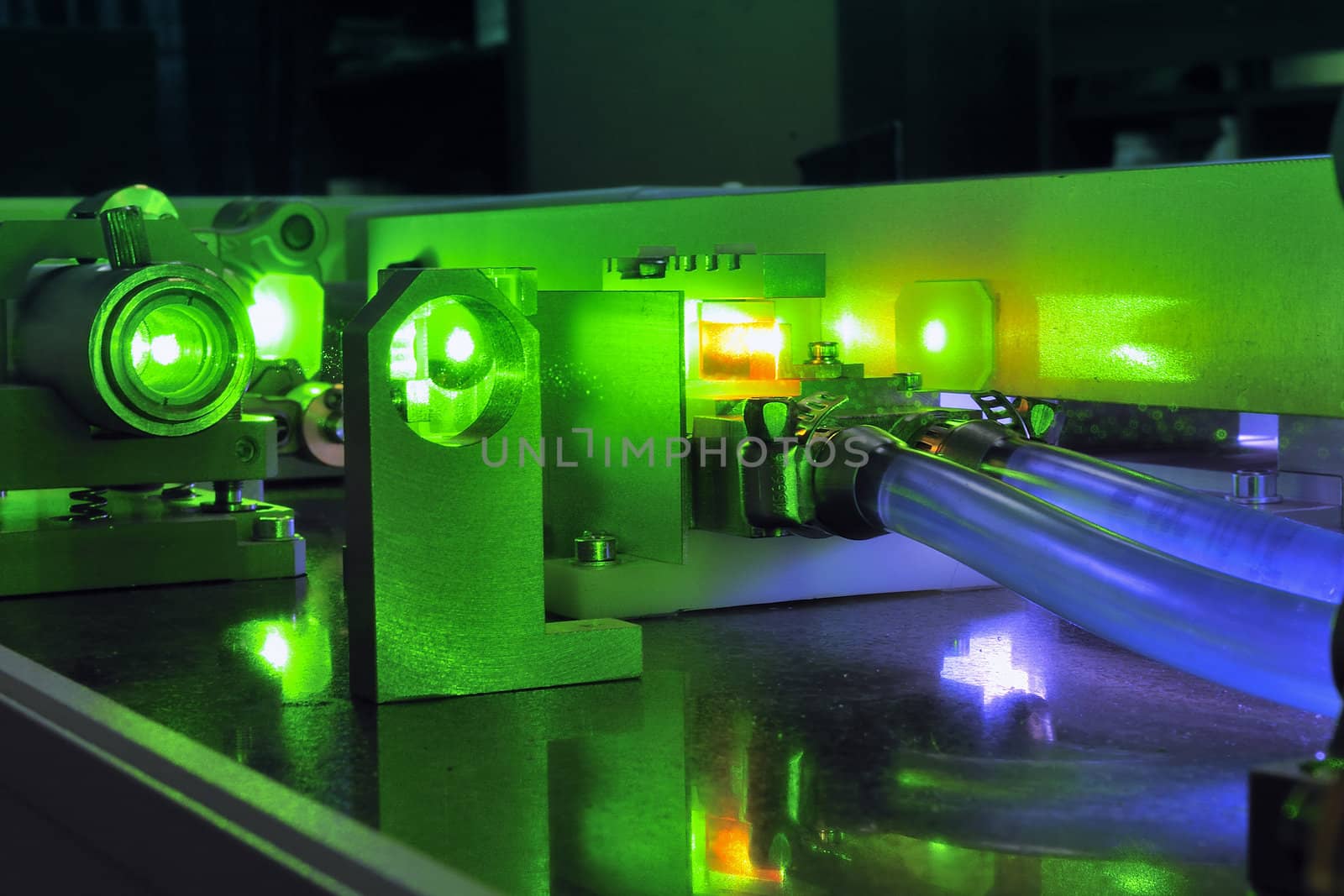 bright green laser light going inside complicate scientific system with cooling hoses inside