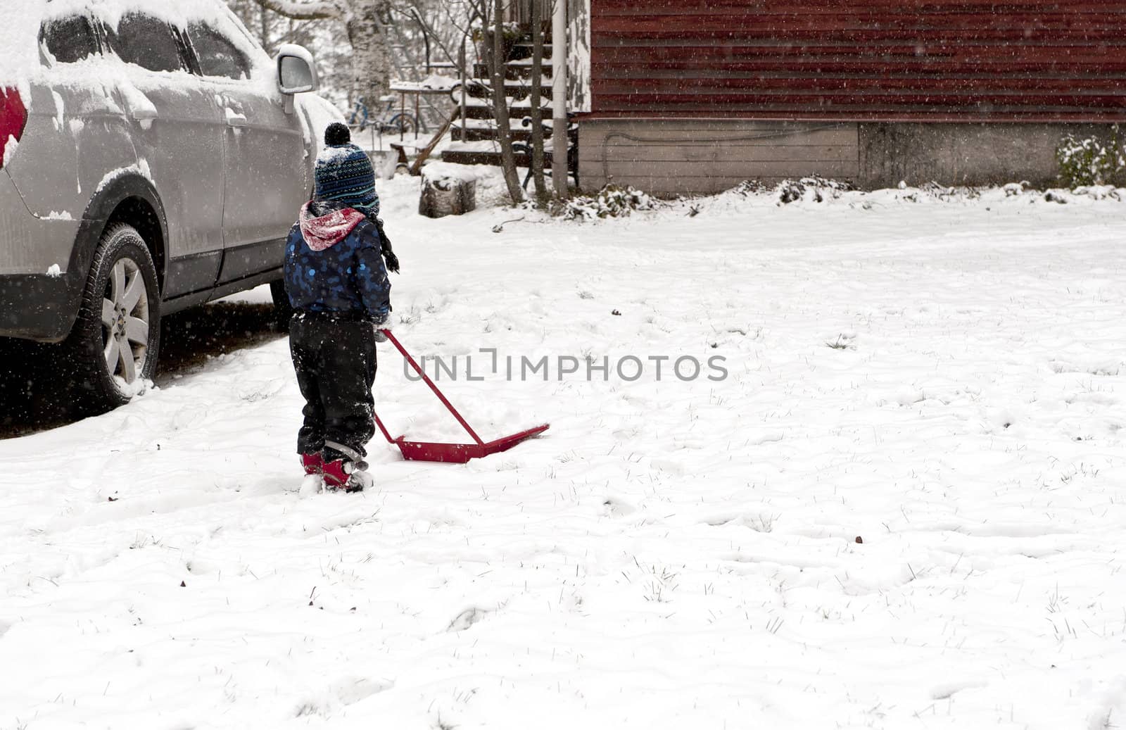 Young boy plowing away snow with a little shovel