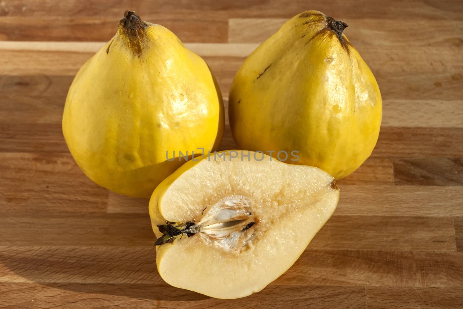 Three and half organic quinces on wooden plate