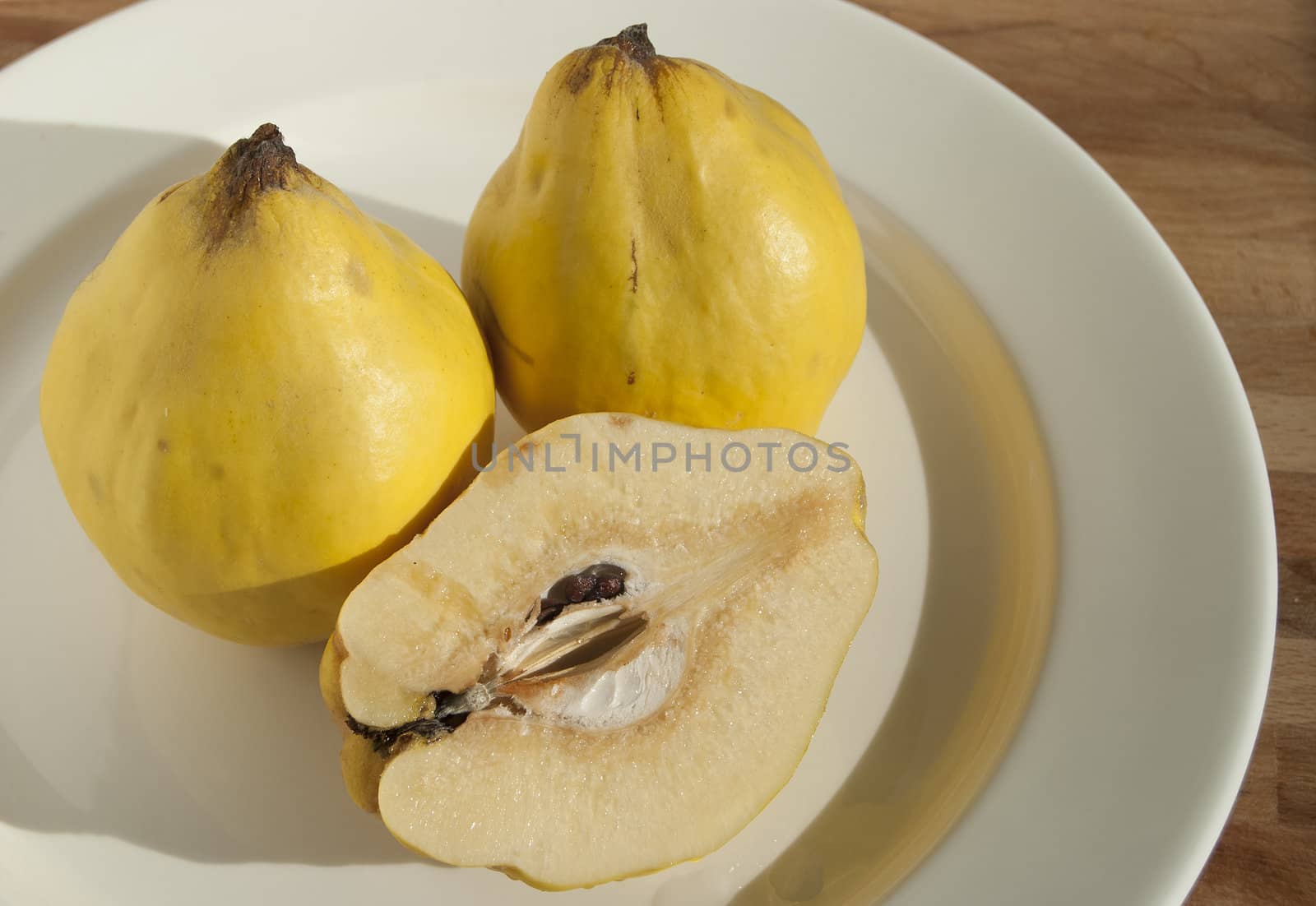 Three and half organic quinces on white plate