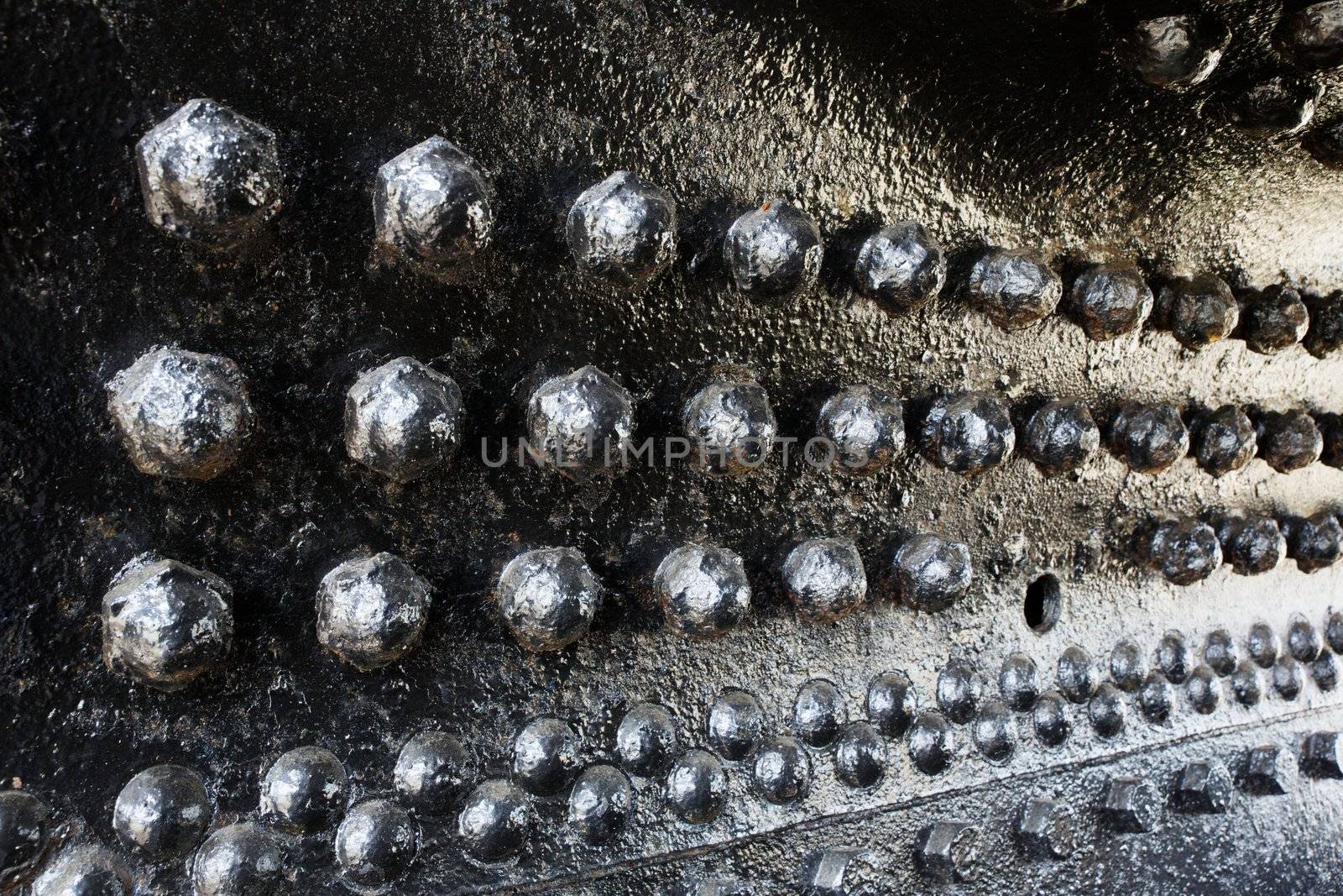 Black rivets in perspective on a train engine boiler