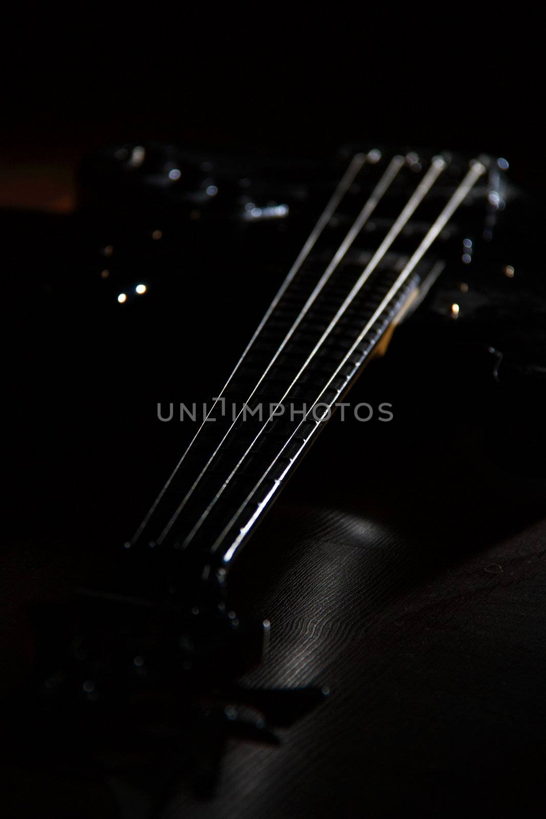 bass guitar with four strings on black ground 