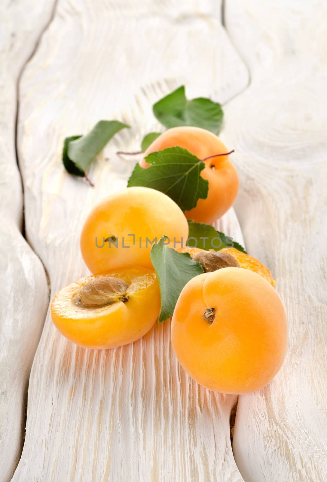 Apricots and leaves on a table by Givaga