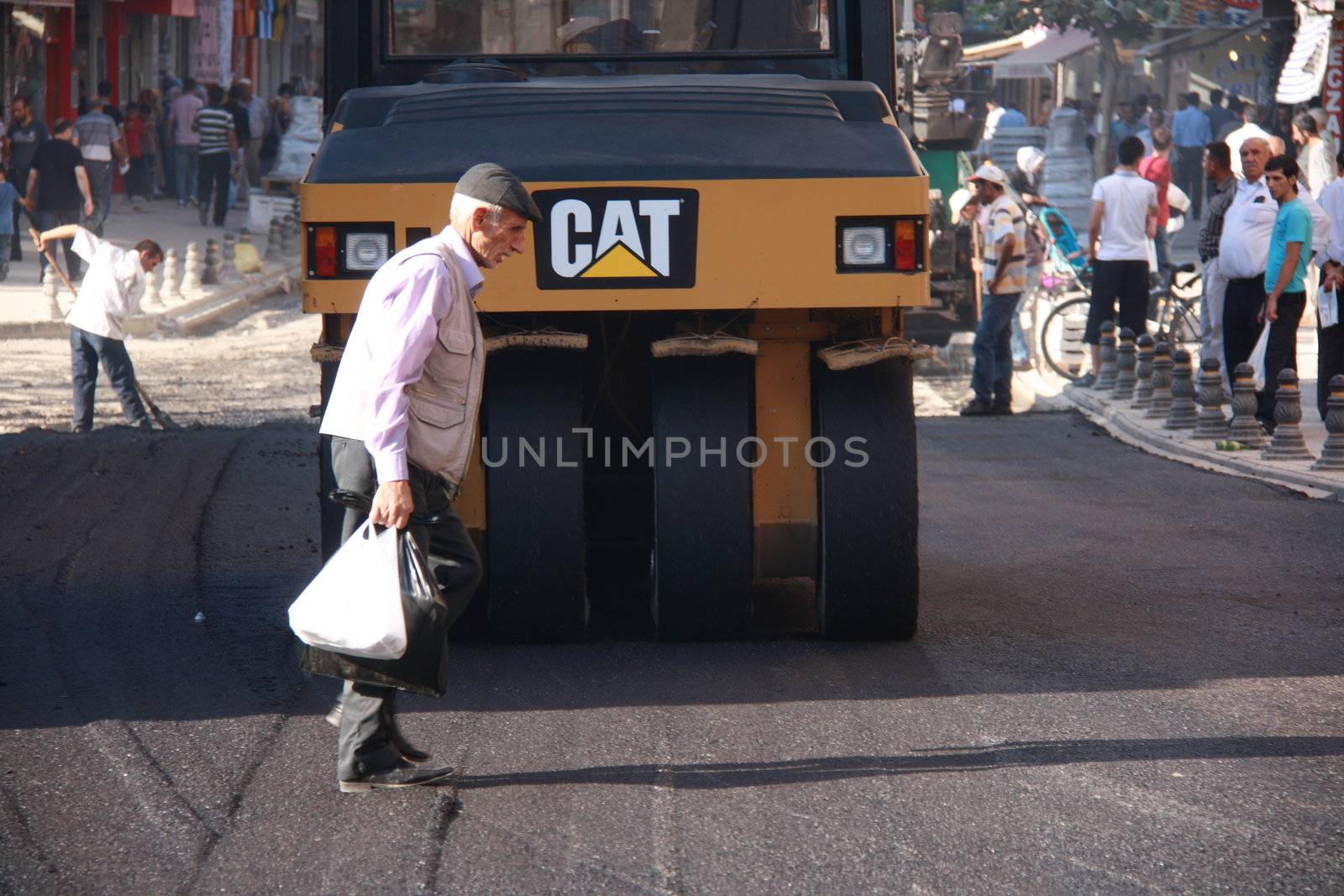 old man walking on asphalt while they constructing in Turkey