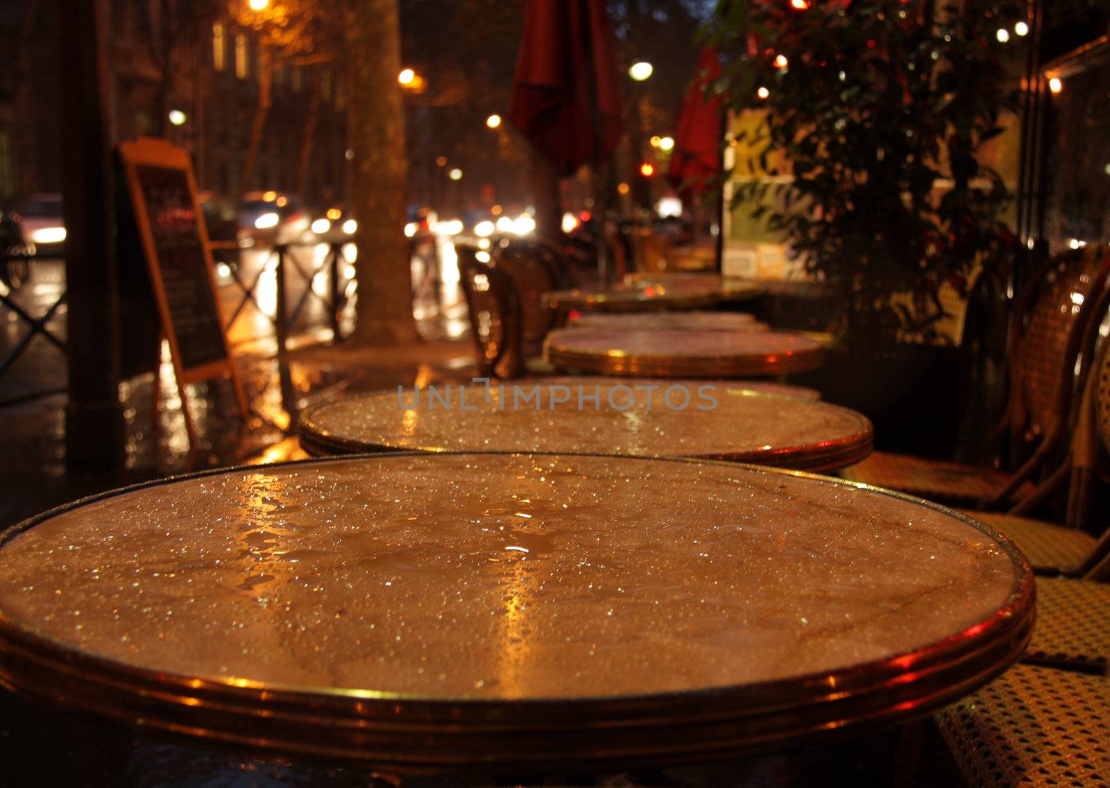 cafe in paris at evening, tables are wet after rain