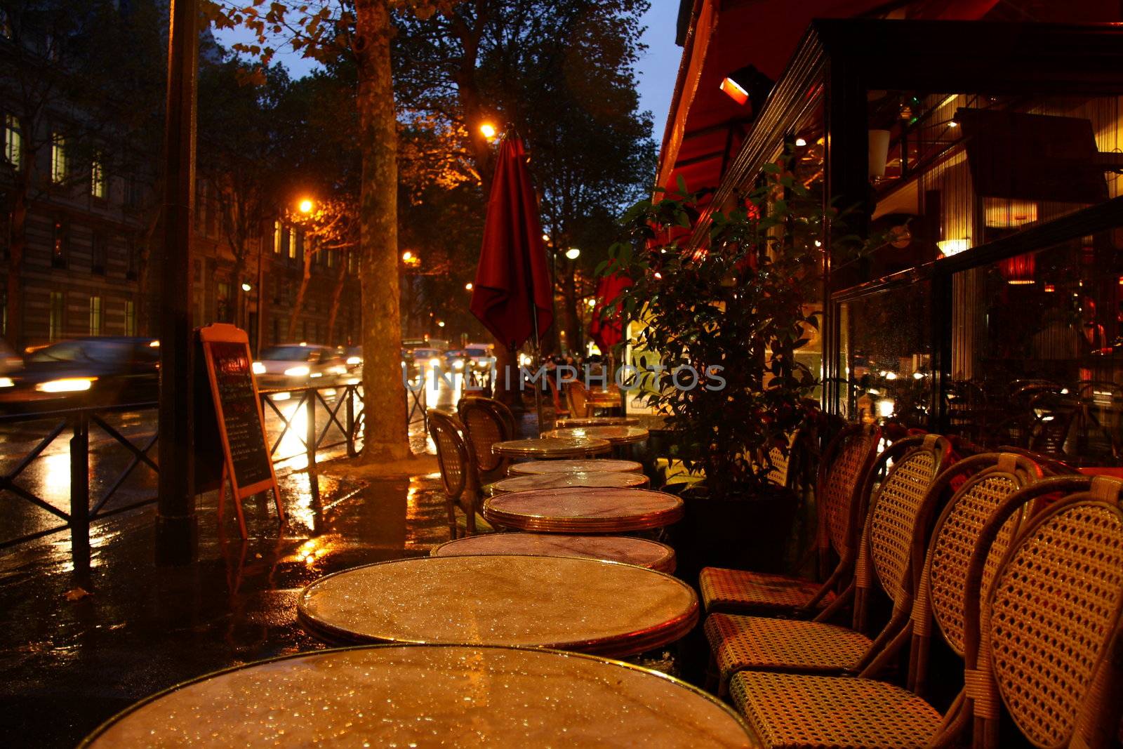 cafe in paris at evening, tables are wet after rain