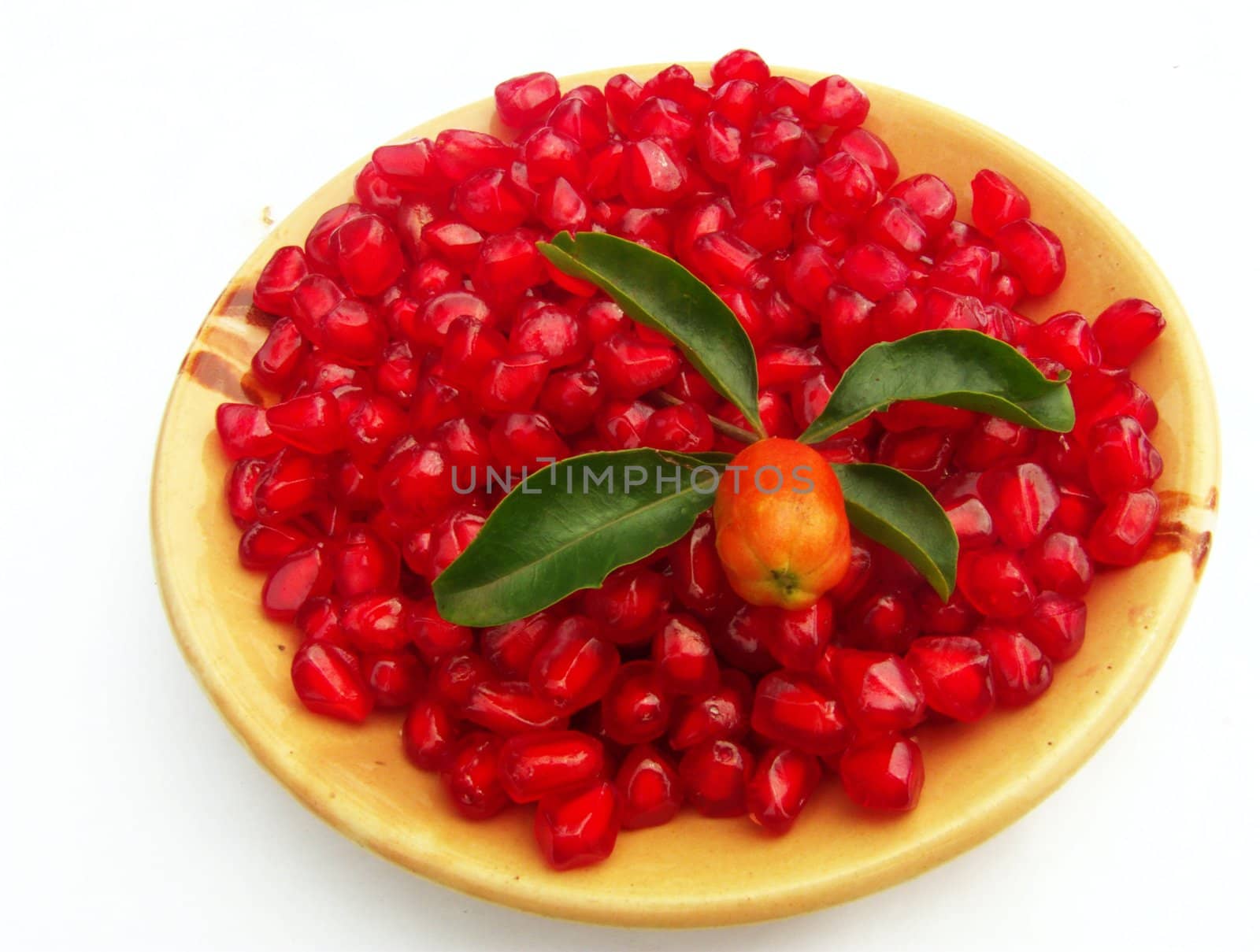 pomegranate (Punica granatum) seeds on a plate with leaves and a bud isolated on white