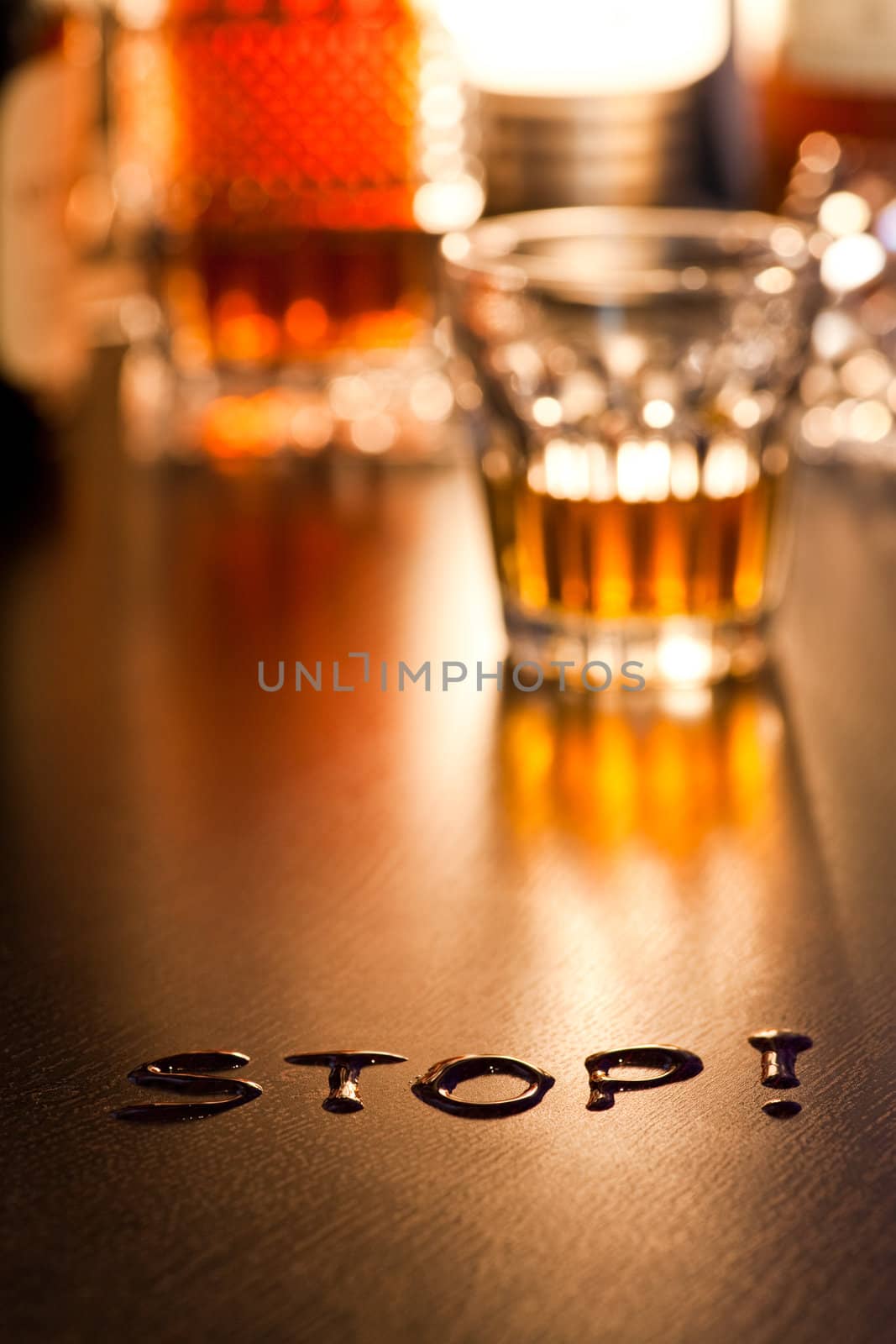 The word Stop with glass of whiskey in background, shallow DOF