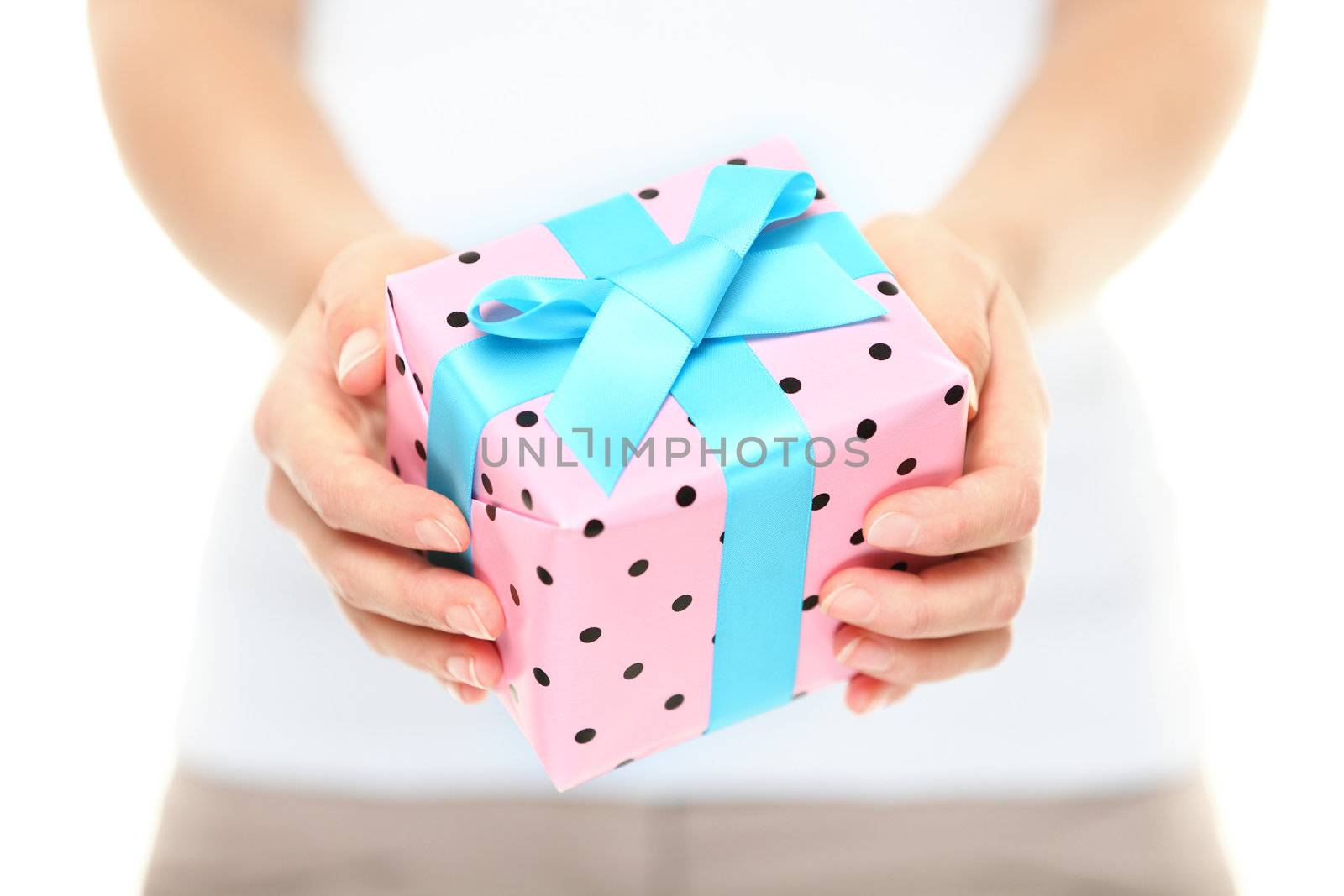 Hands holding a decorative Xmas gift with pretty pink polka dot paper tied with a turquoise ribbon and bow for your Christmas greeting