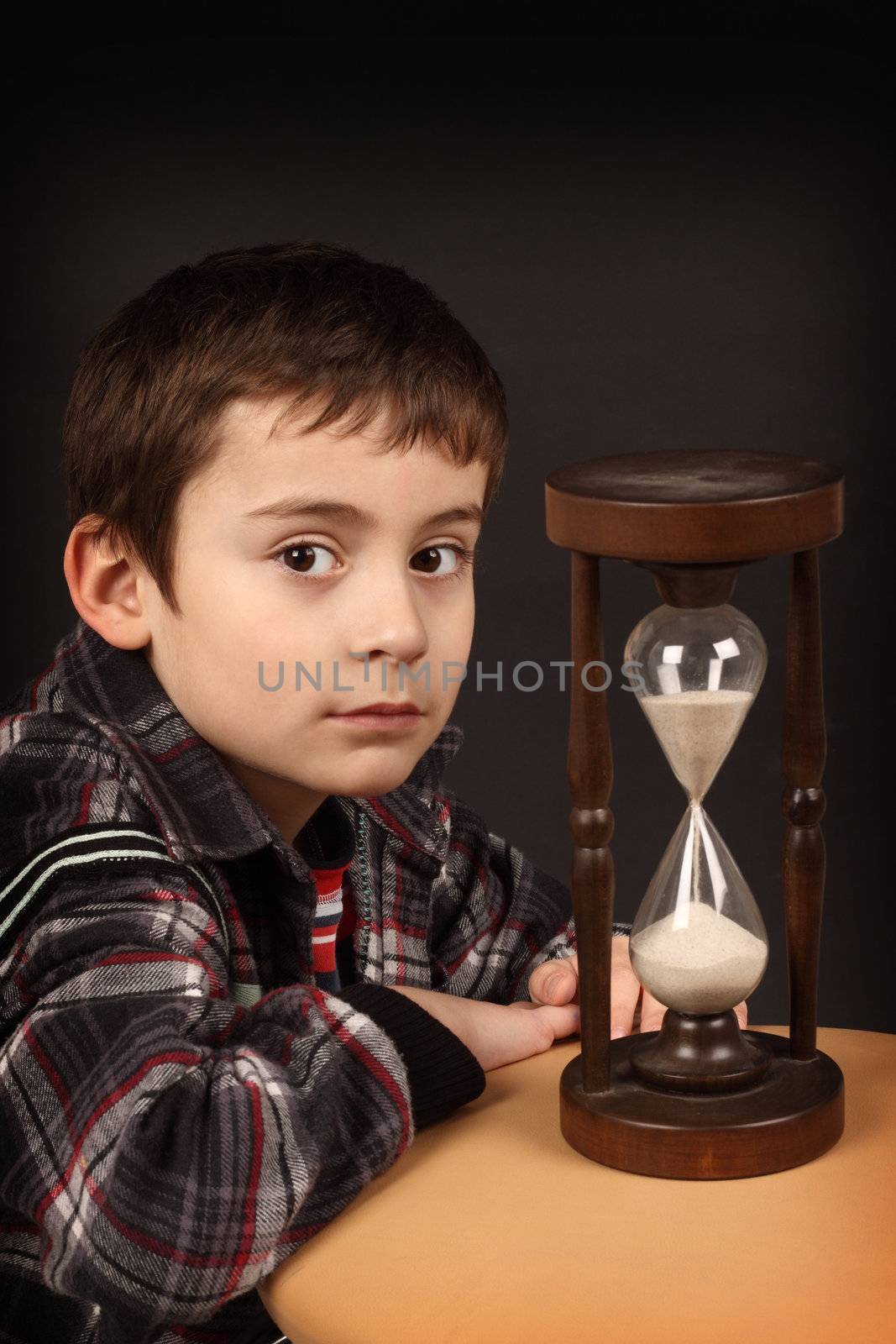 Portrait of a schoolboy with hour-glass. Time to school concept 