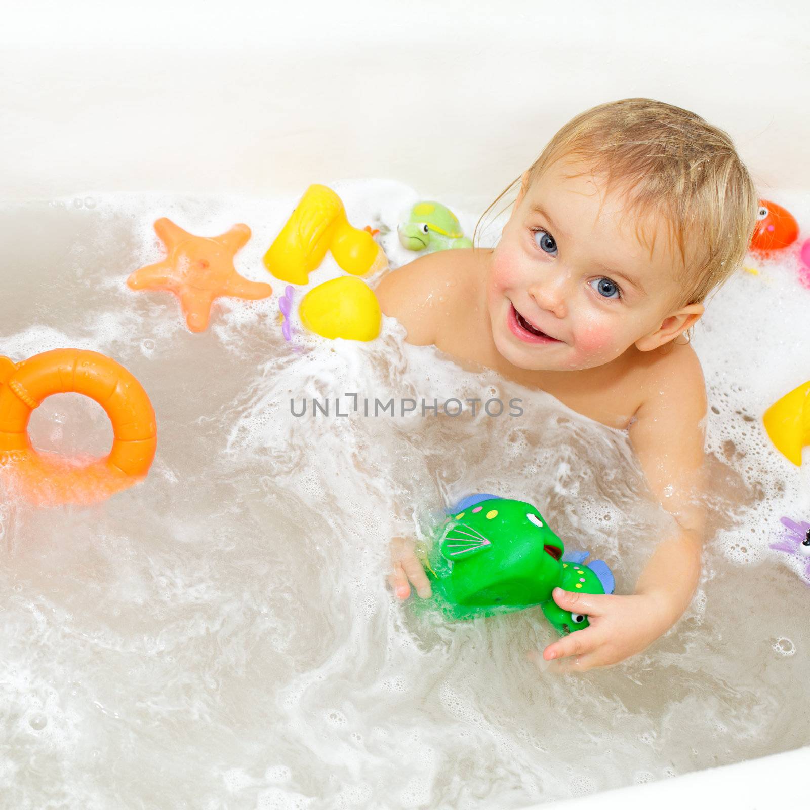 Cute little girl bathing with toys