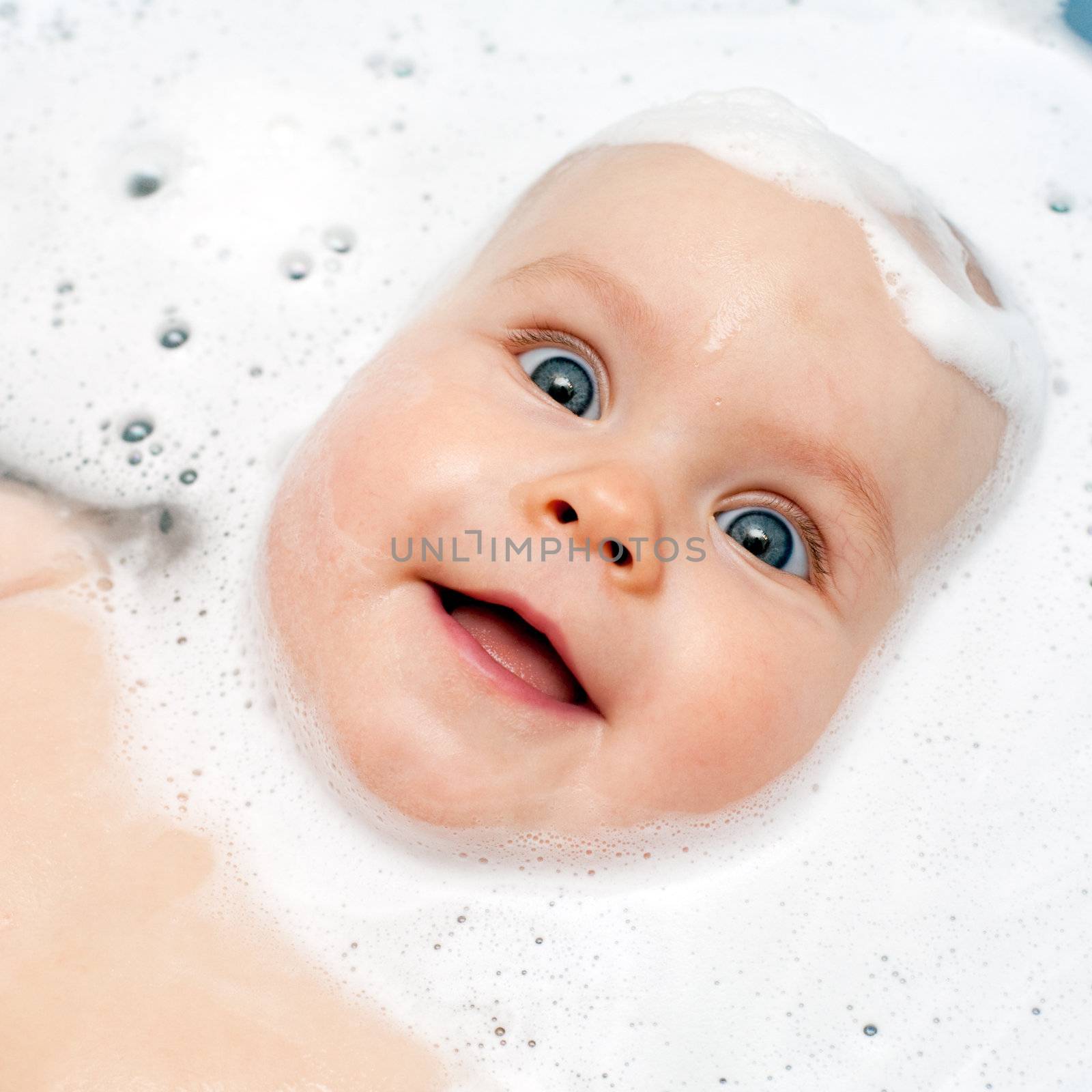 Little baby girl bathing in soapsuds