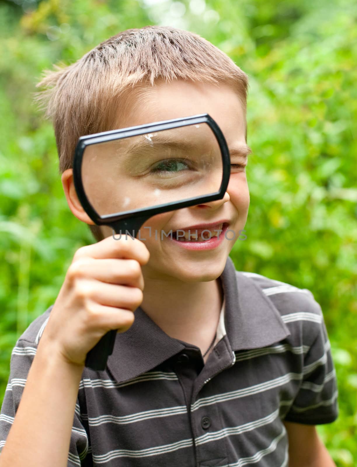 Cheerful boy looking through hand magnifier, shallow DOF