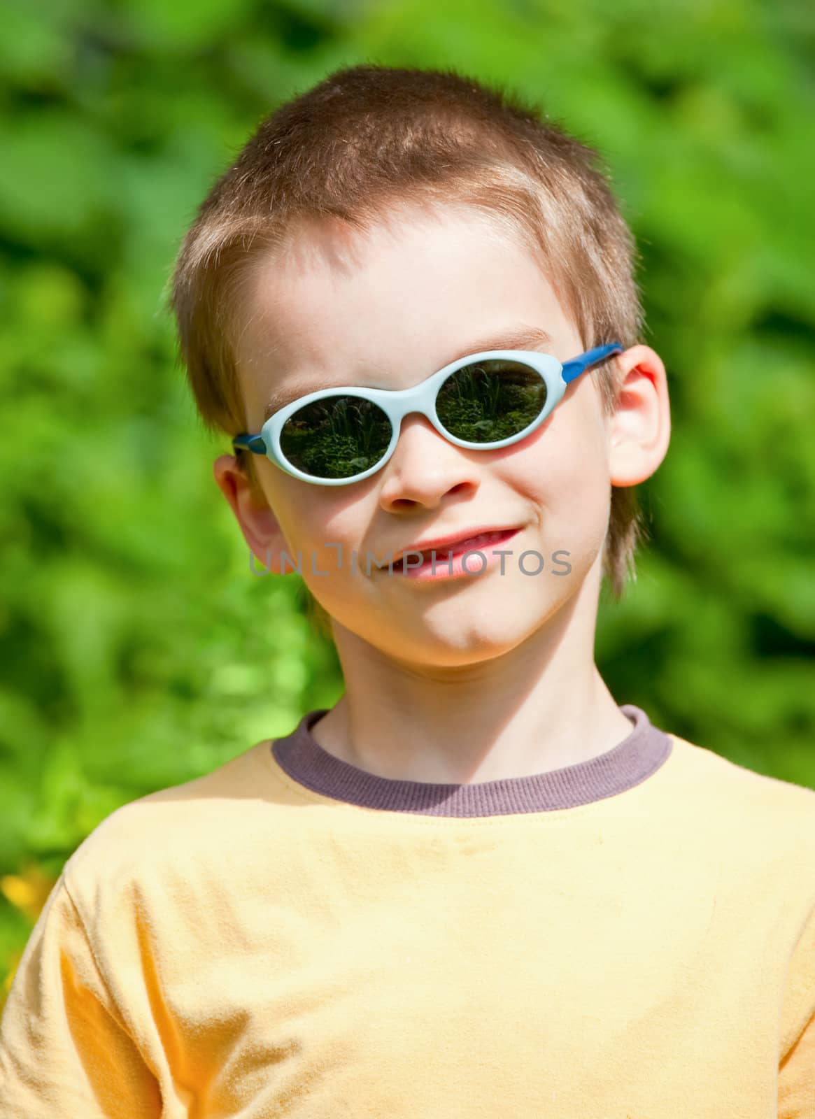 Portrait of a young boy with sunglasses and yellow shirt outdoors