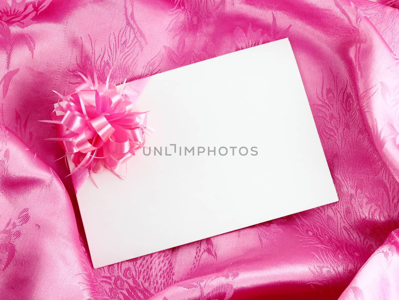 Blank gift card with ribbon on pink satin