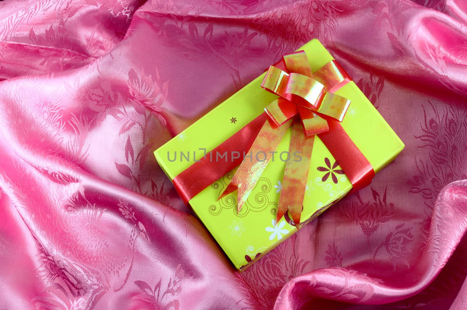yellow gift box with ribbon on pink satin by geargodz