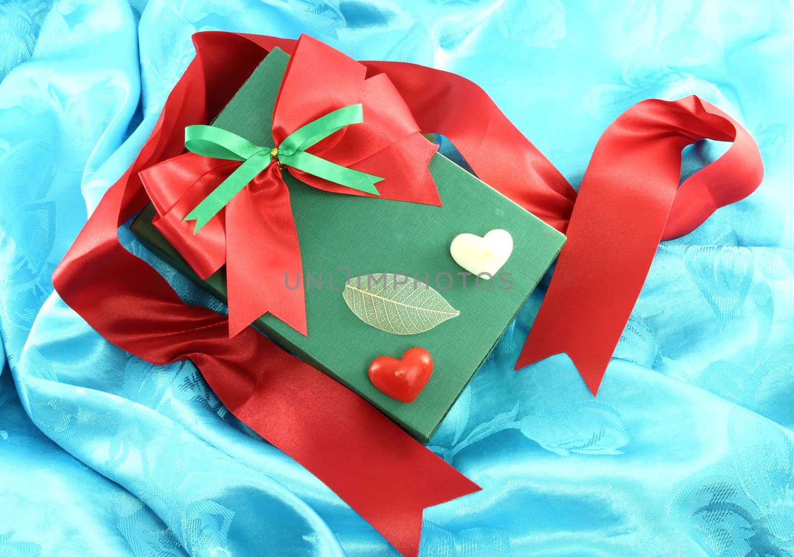 green gift box with red ribbon on blue satin by geargodz