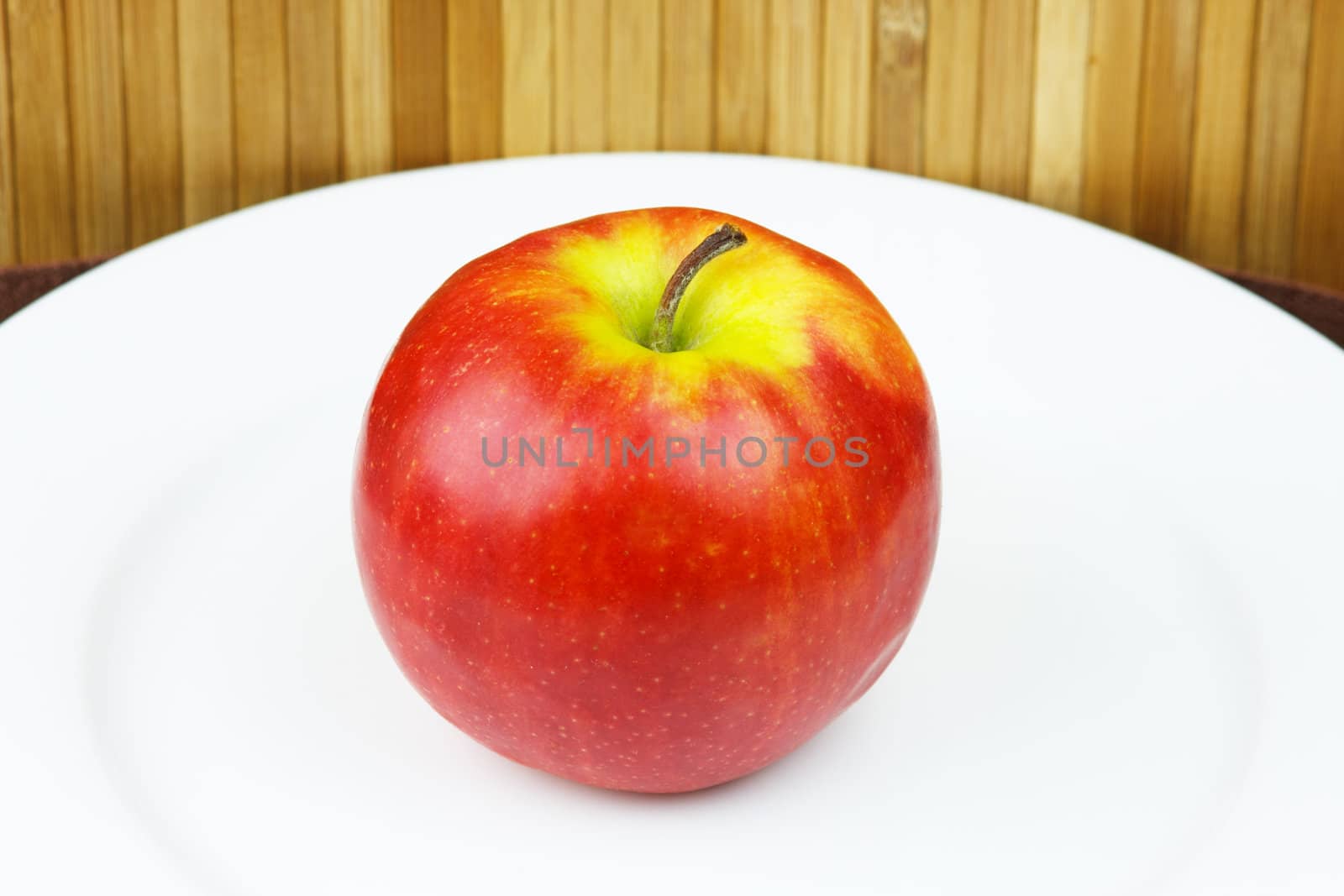 apple on a plate standing on a bamboo napkin