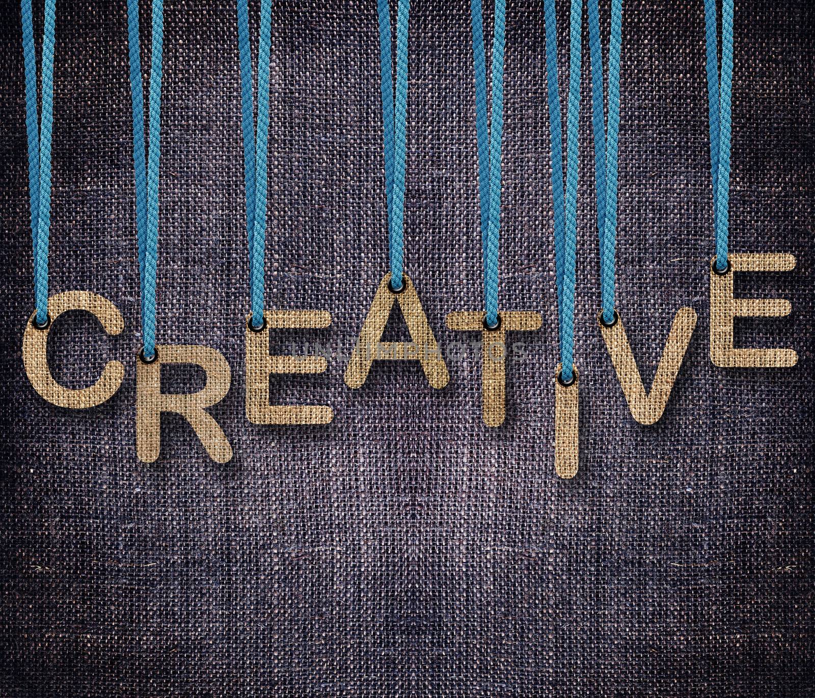 Creative word hunging by rope as puppeteer on sackcloth background.