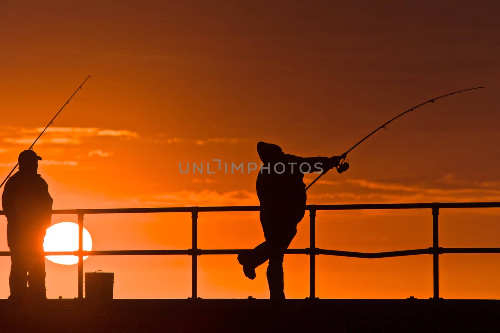 Men fishing, silhouettes with sunset