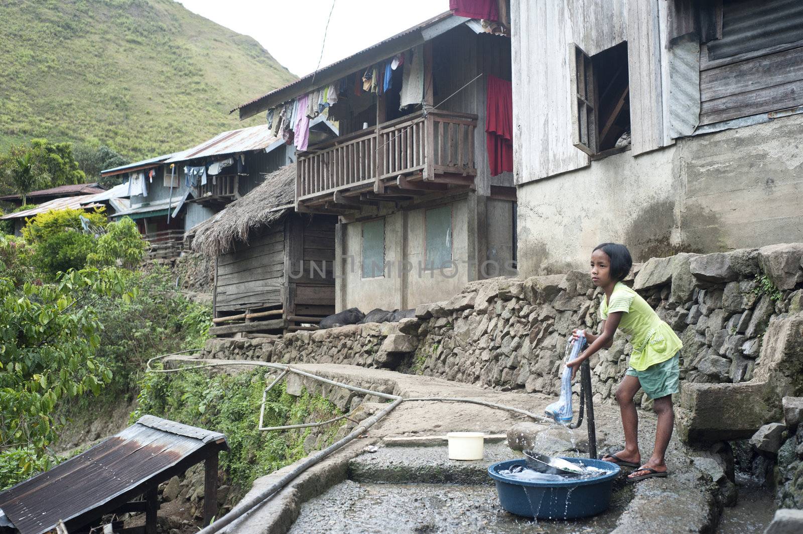 Sagada, Philippines - March 23, 2012:  Girl washing clothes in the small village in Philippines.  About 12 per cent of Philippines children between the ages of five and 14 are forced to work. 