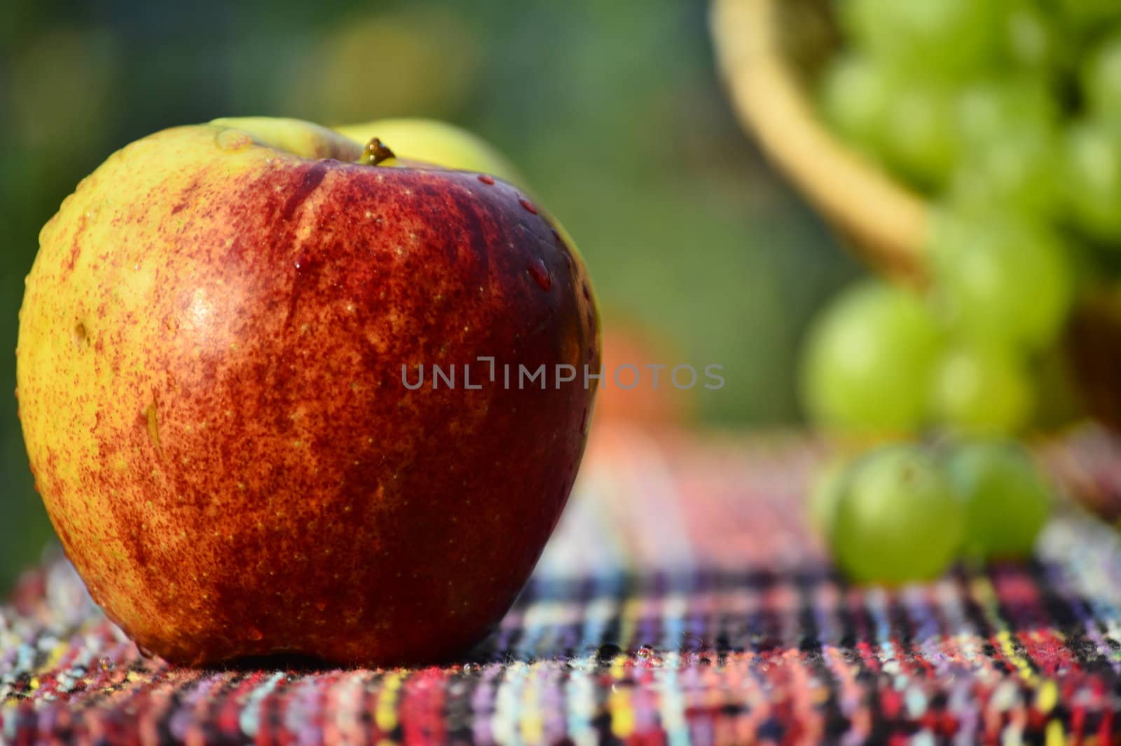 red apple in front of white and rose grapes on a table