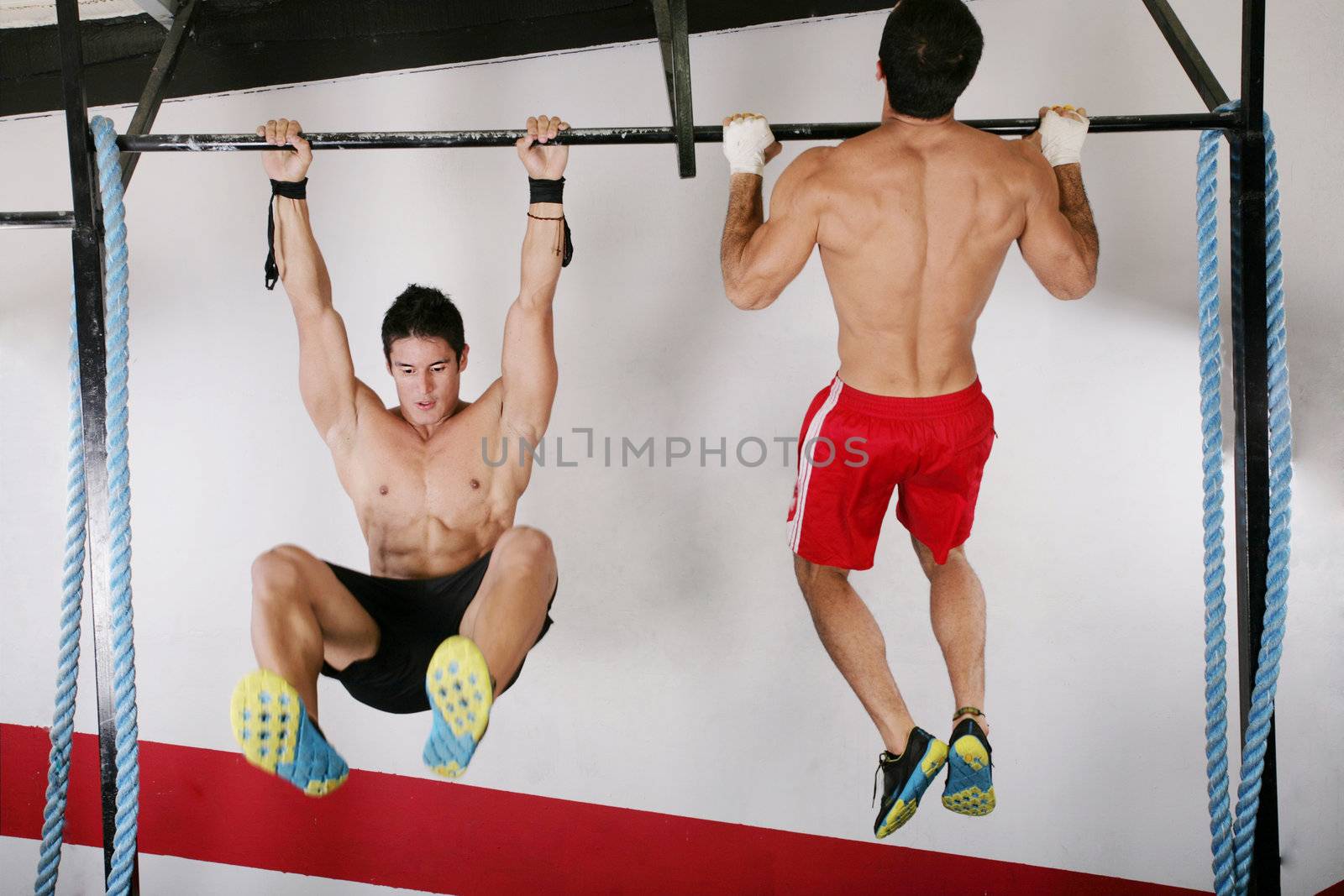 athletic group executing exercise tightening on horizontal bar. by dacasdo
