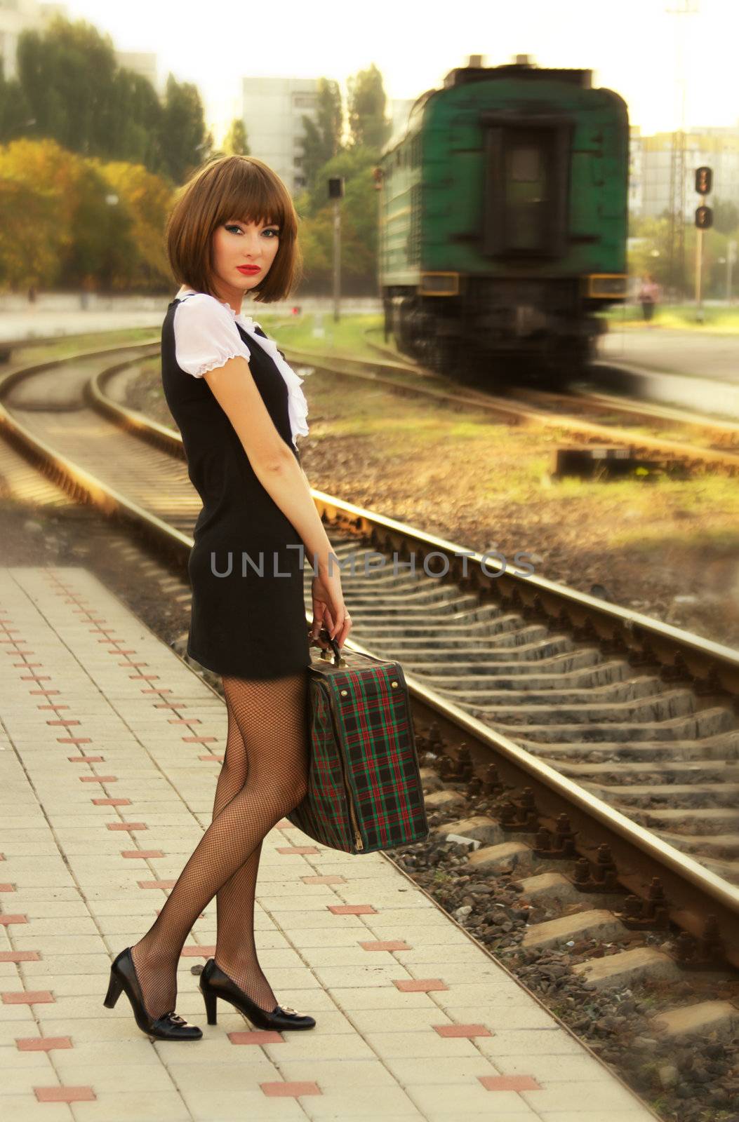 Retro-styled woman with suitcase on the platform waiting for train
