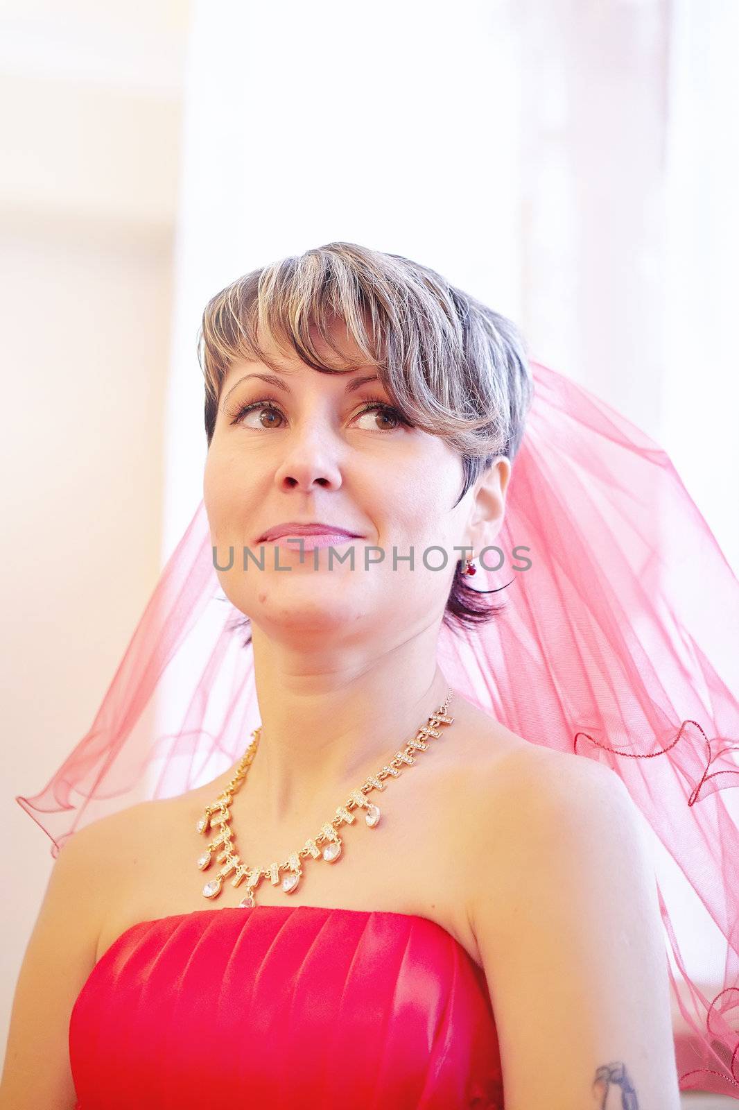 Portrait of the girl bride in a red dress on a light background