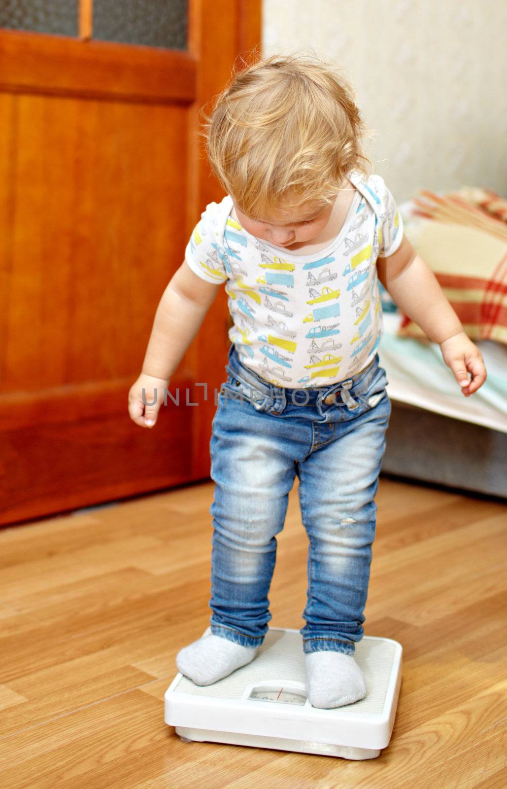 Little boy is standing on the scales checking his weight.