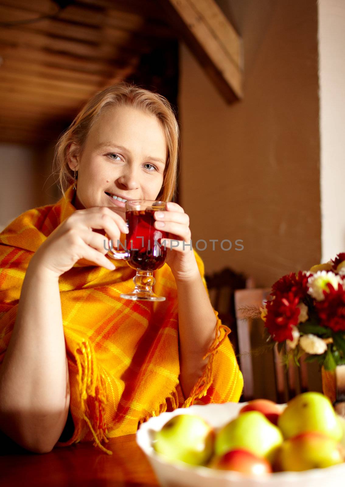 Young beautiful woman with birthmark on her face is drinking carcade tea and smiling at the wooden vintage style restaurant.