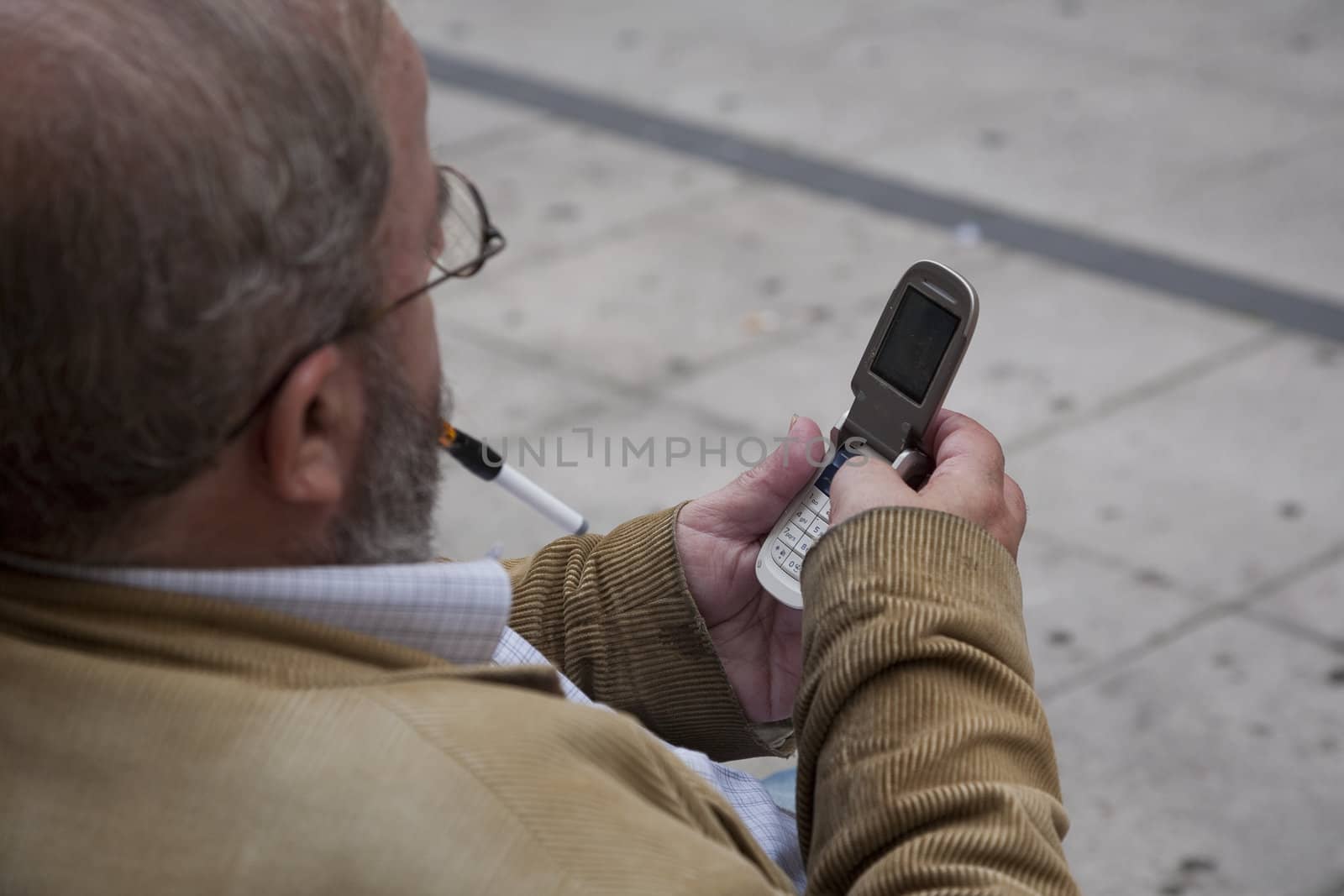 SENIOR MAN WITH MOBILE, OVIEDO, SPAIN - SEPTEMBER 17: Caucasian male with mobile phone is texting a message on a bench in city of Oviedo, Spain, on September 17, 2012.