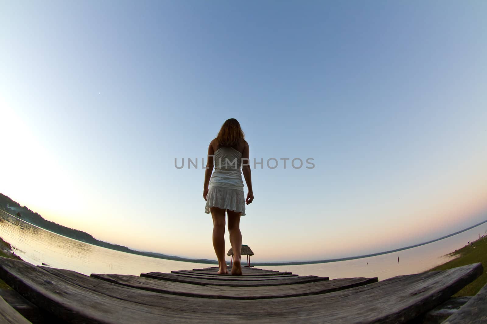 A young woman investigates the early morning lake.