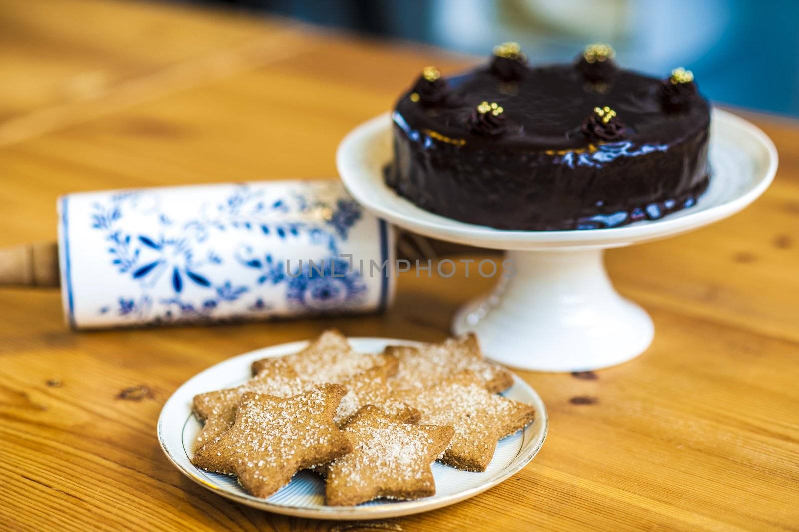 Rich chocolate cake and star shaped cookies ready to be served. Rolling pin on the table.