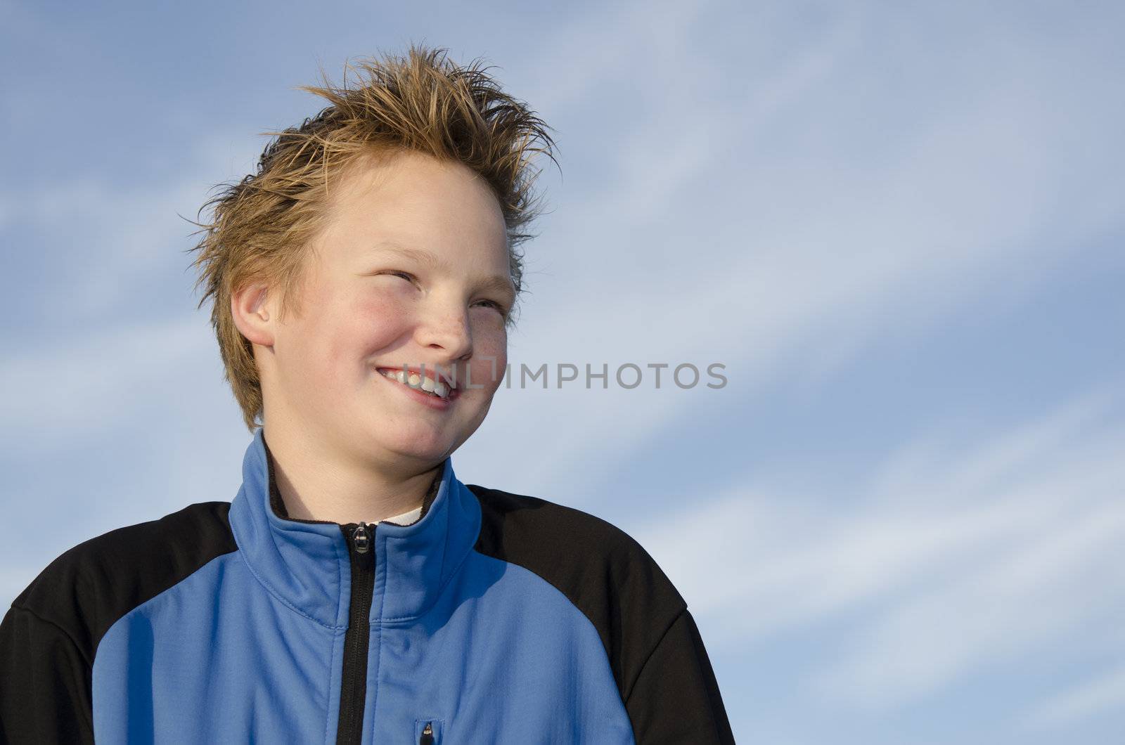 Portrait of happy teen with spiky hairstyle against blue sky