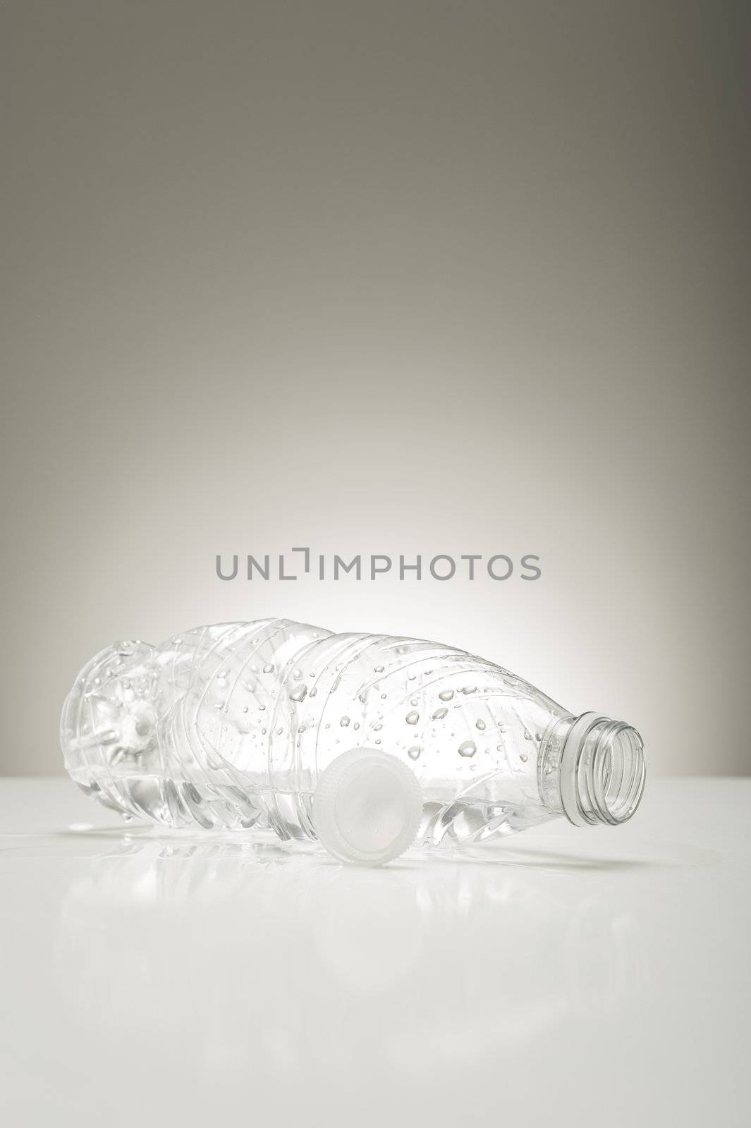 Clear plastic bottle coated in water droplets lying on its side on a studio countertop conceptual of clean pure fresh bottled water for good health